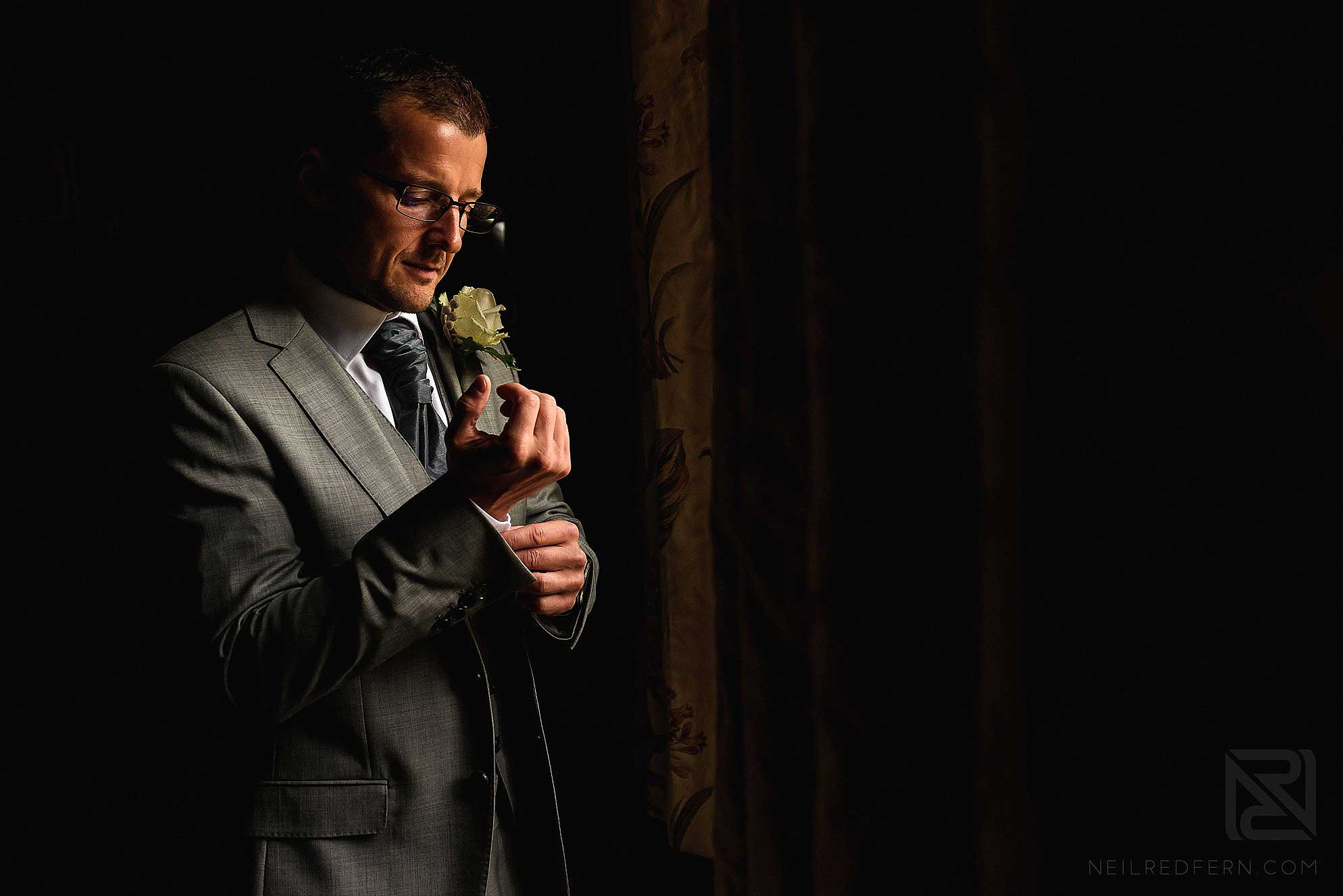 groom putting on cuff links