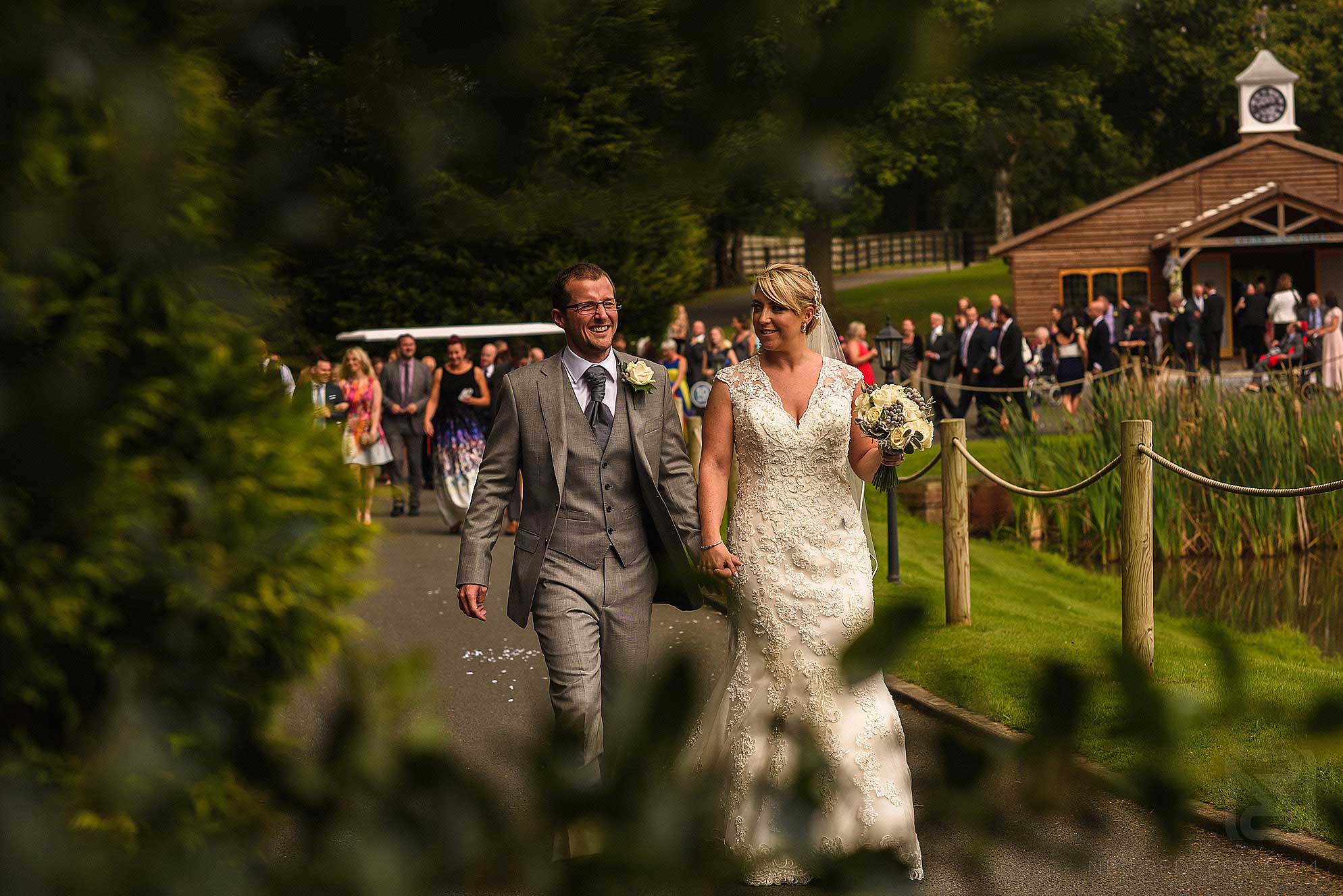 bride and groom walking through gardens at Colshaw Hall
