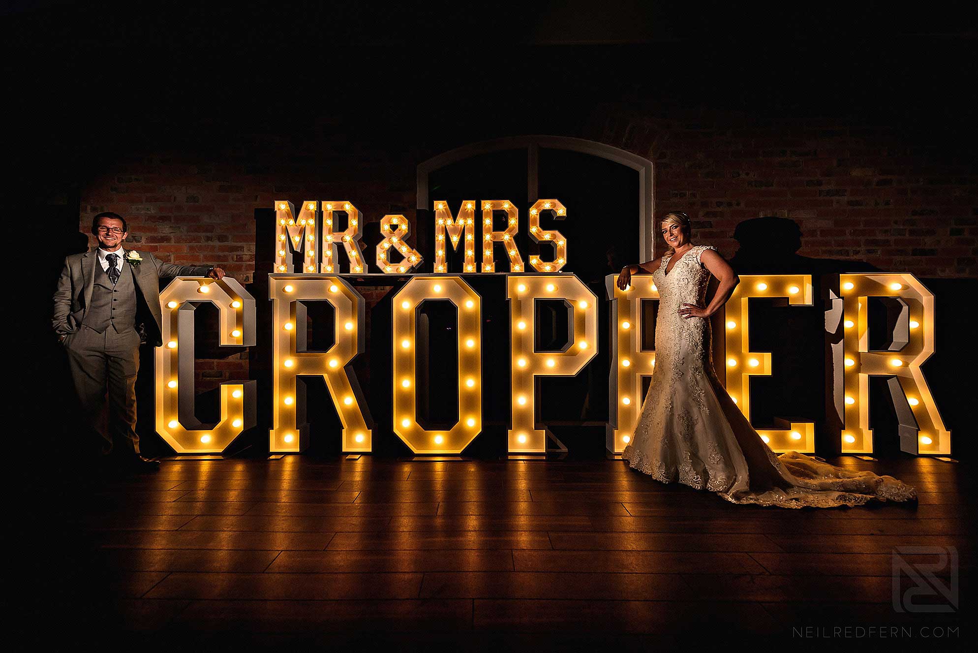 couple stood in front of large letters at wedding