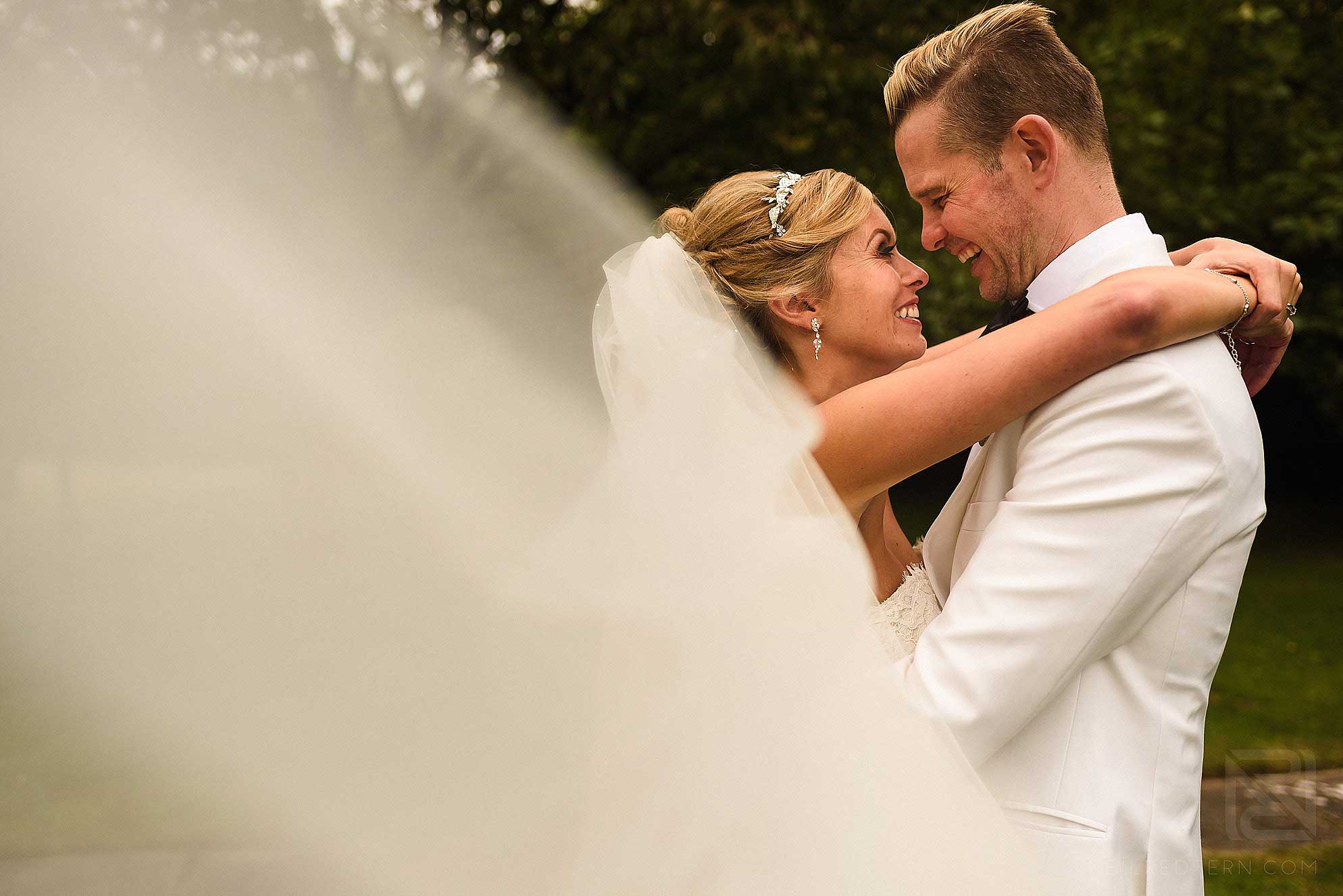 bride and groom smiling with veil