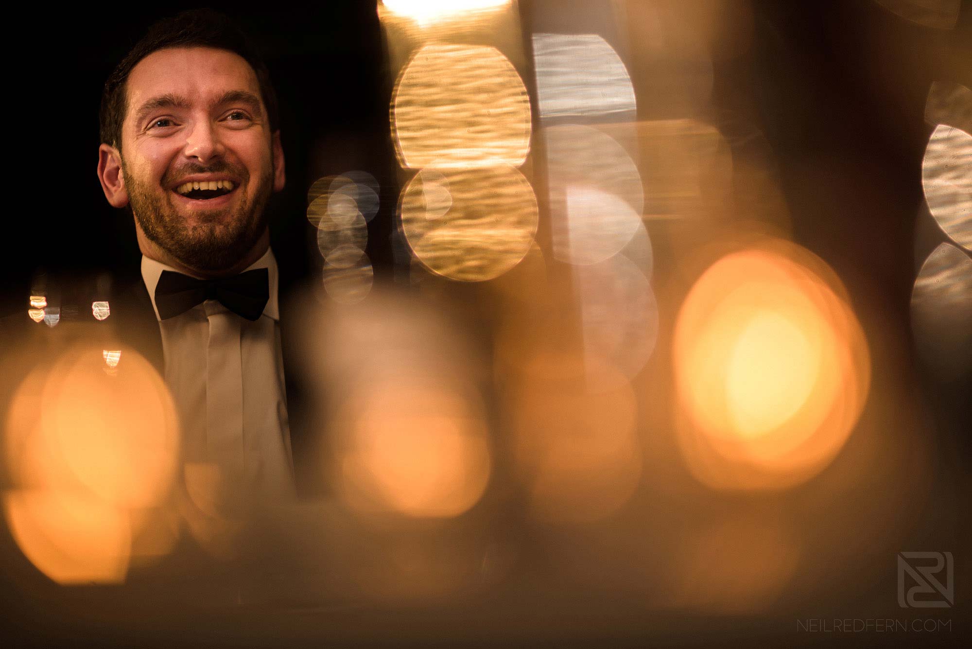 groom laughing during best man's speech at wedding
