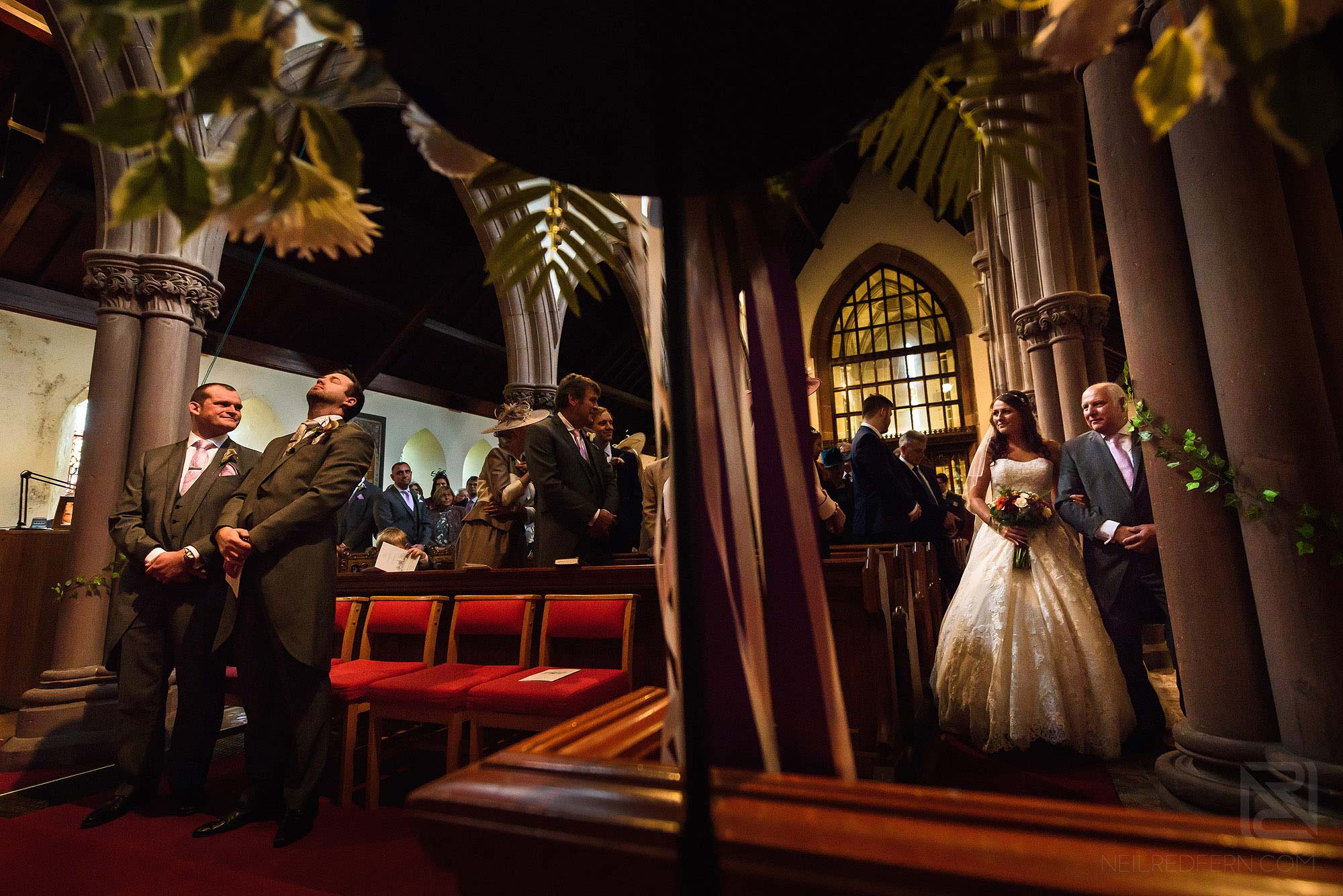 bride walking down the aisle looking at emotional groom