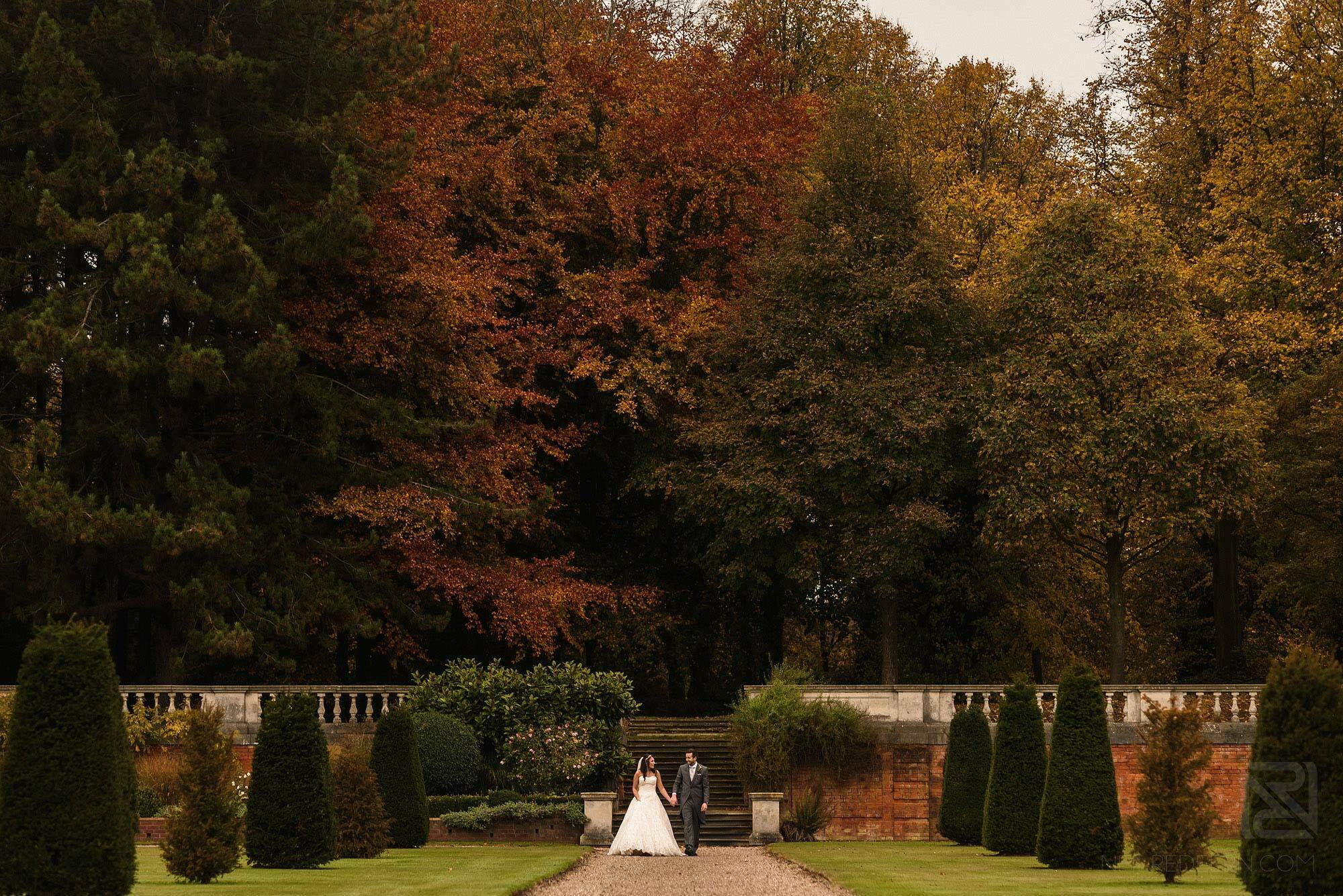 wide angle photograph of newlyweds walking through gardens at Knowsley Hall