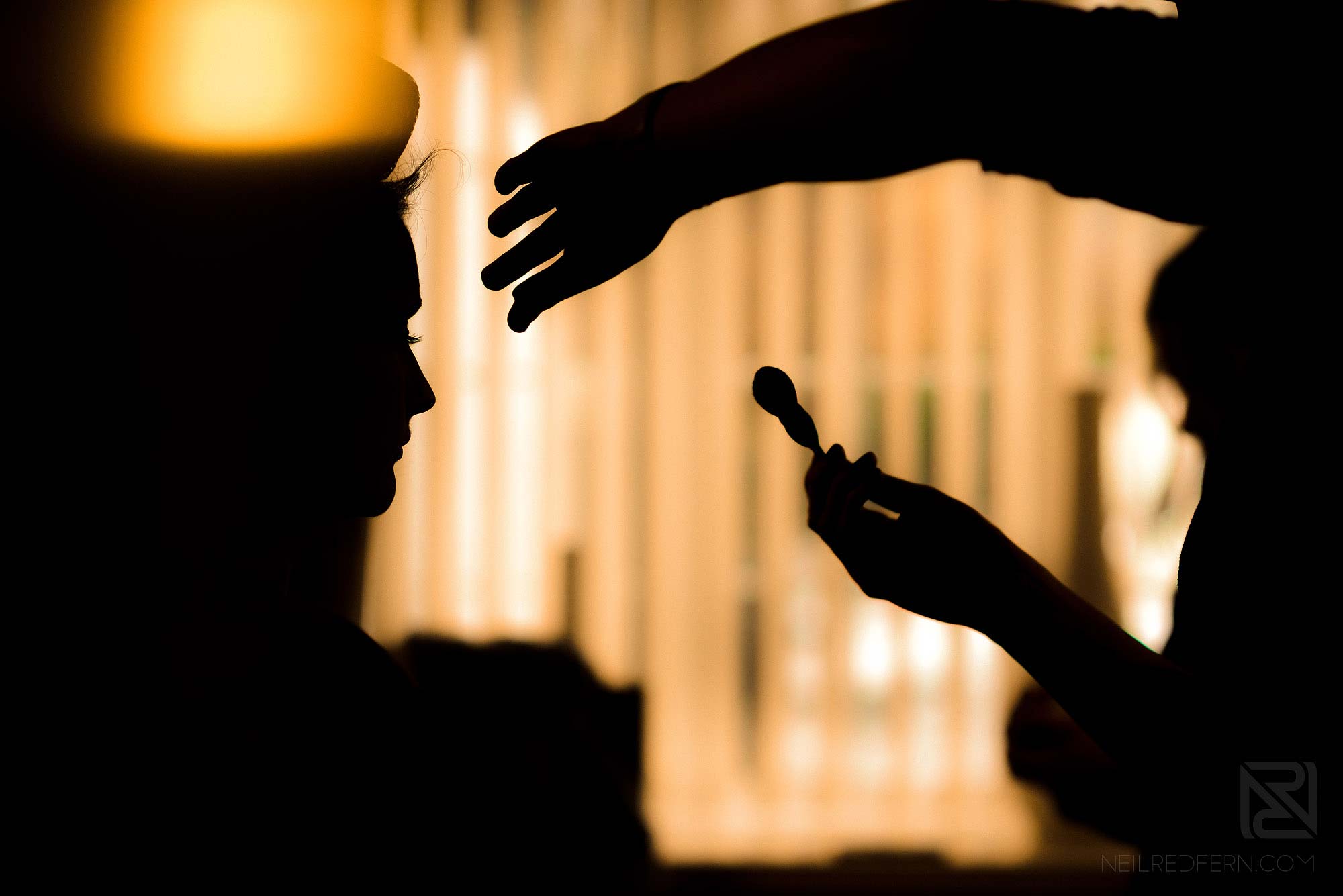 silhouette of bride having make up put on