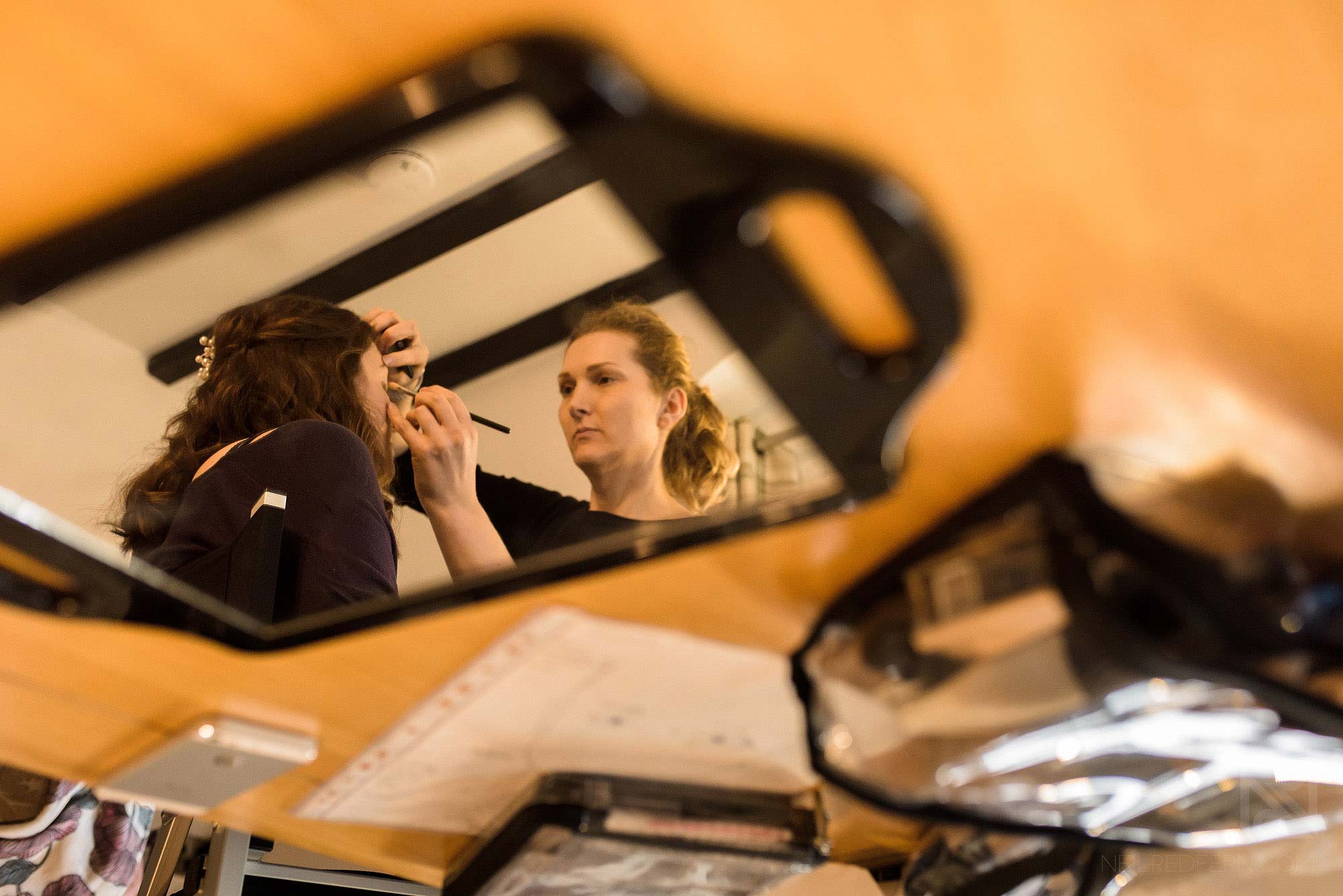 reflection photograph of bridesmaid having make up put on