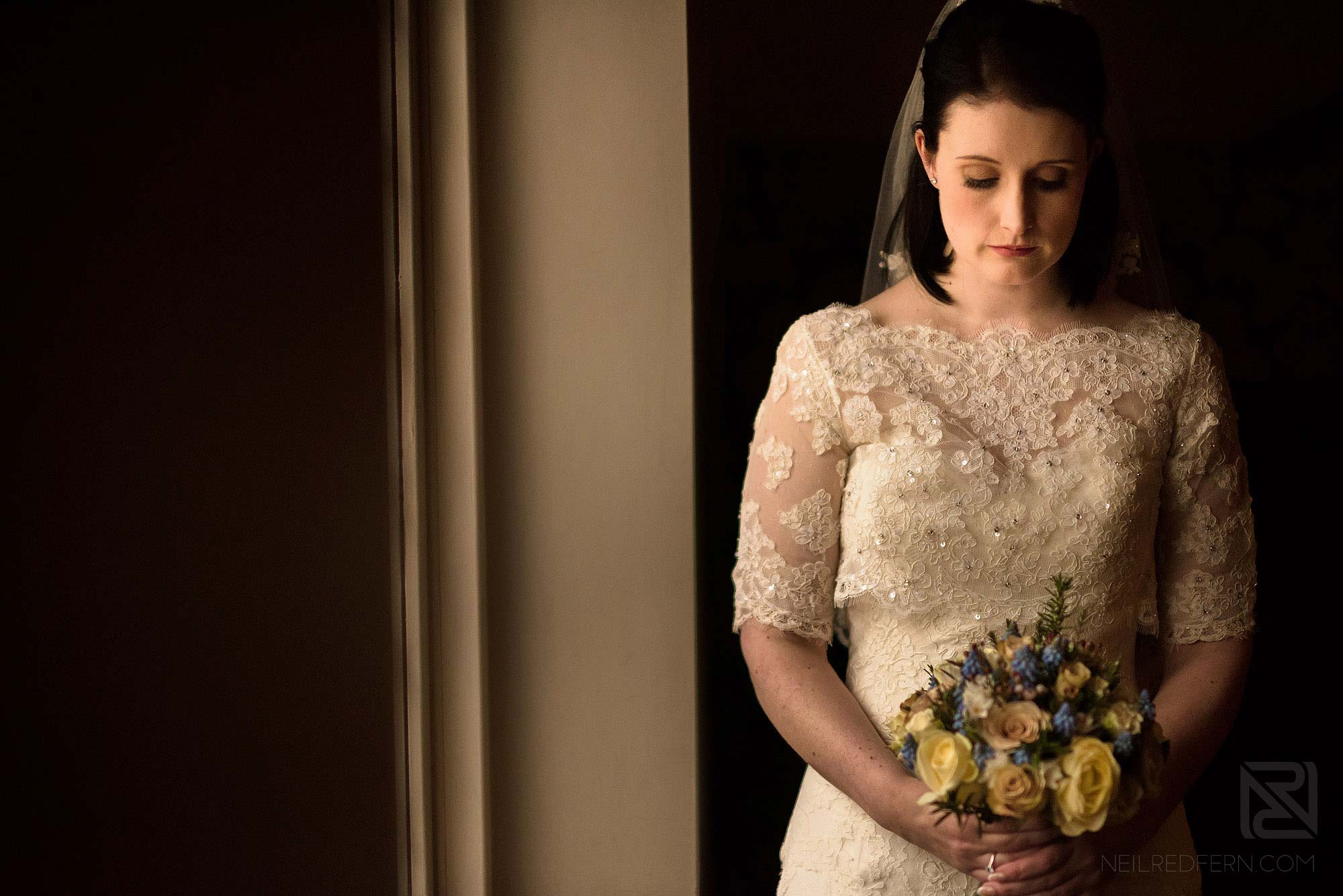 portrait photograph of bride with flowers next to a window
