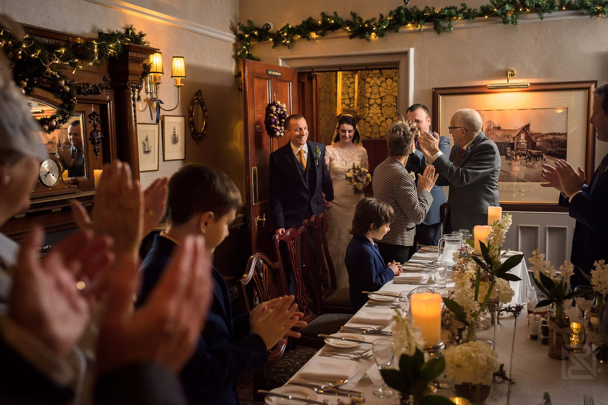 bride and groom being welcomed in to wedding breakfast by guests