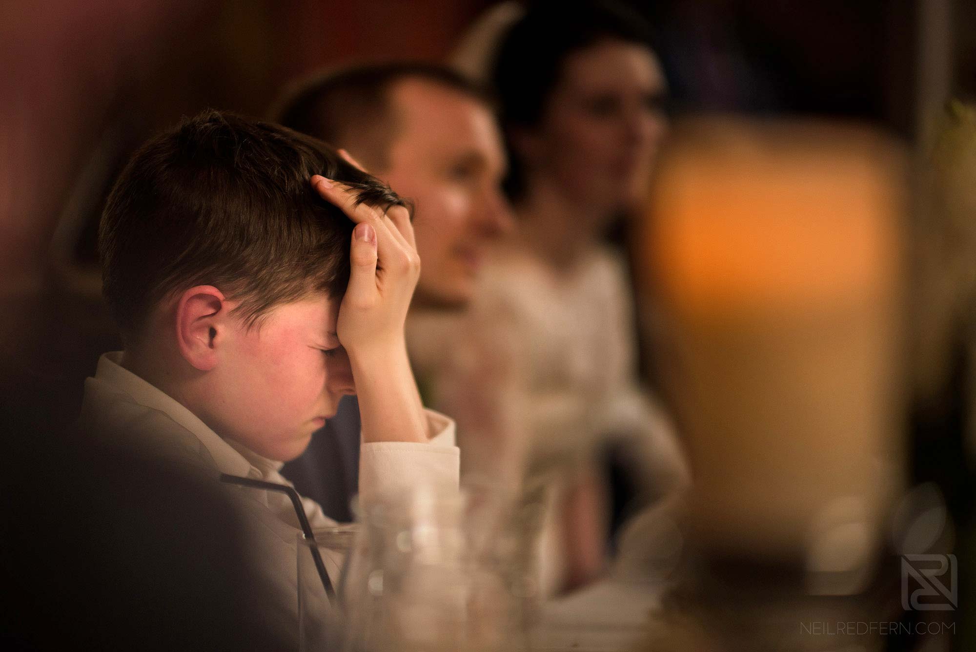 page boy with hands over face during best man's wedding speech
