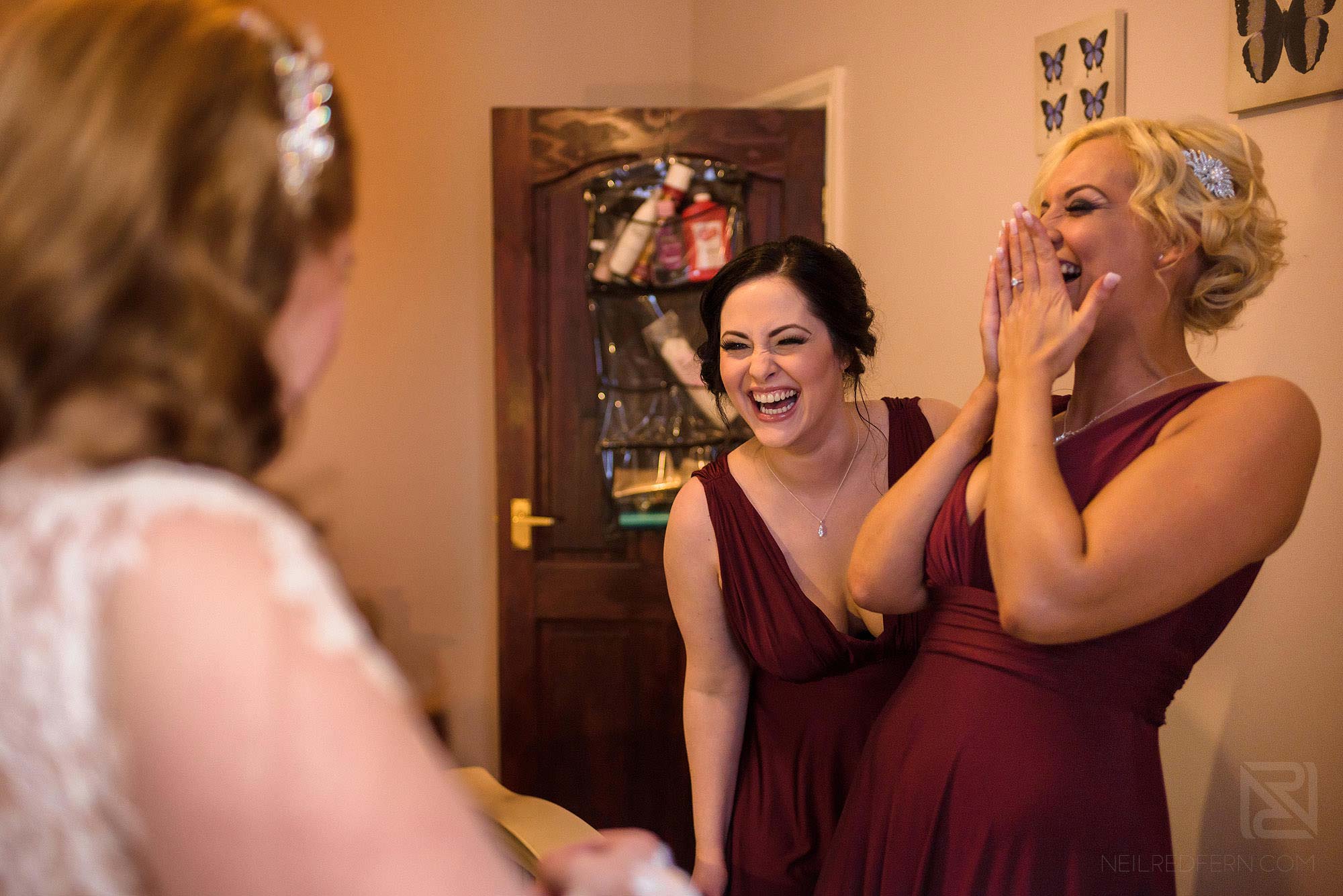 Manchester Museum wedding photography 11 bride putting on wedding dress with bridesmaids laughing