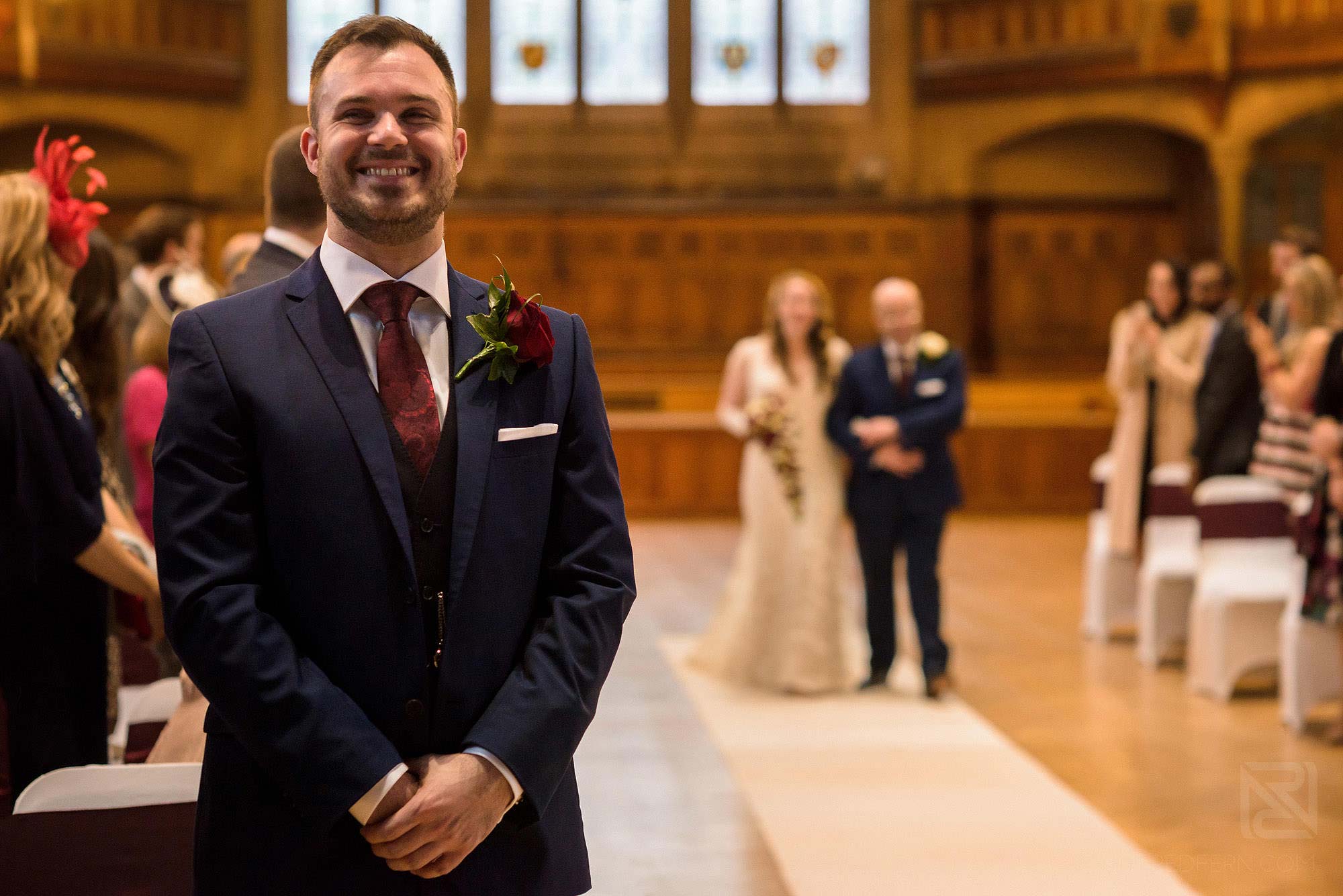 Manchester Museum wedding photography 14 groom smiling as bride walks down aisle in Whitworth Hall in Manchester