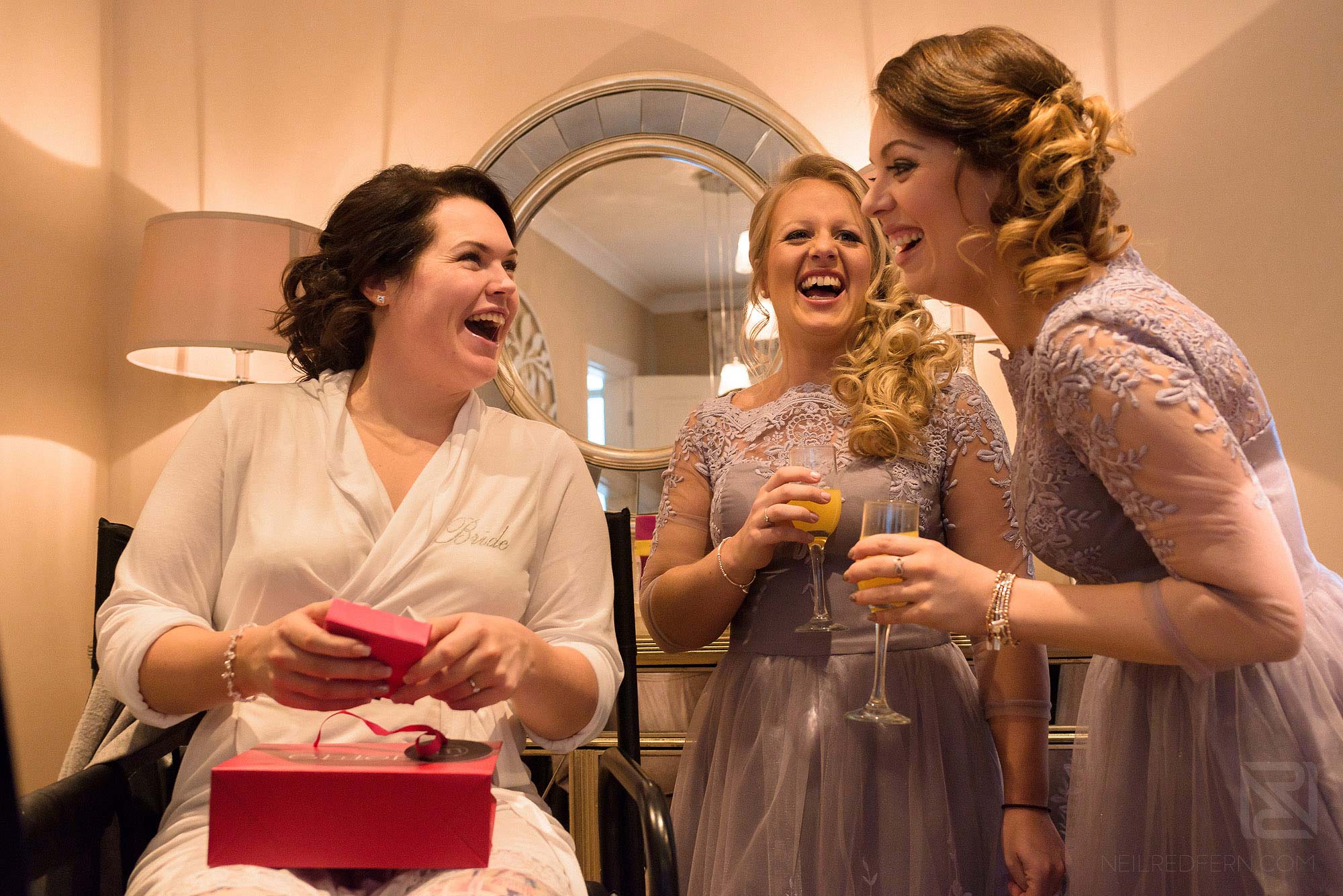 bridesmaids laughing as bride opens wedding gift