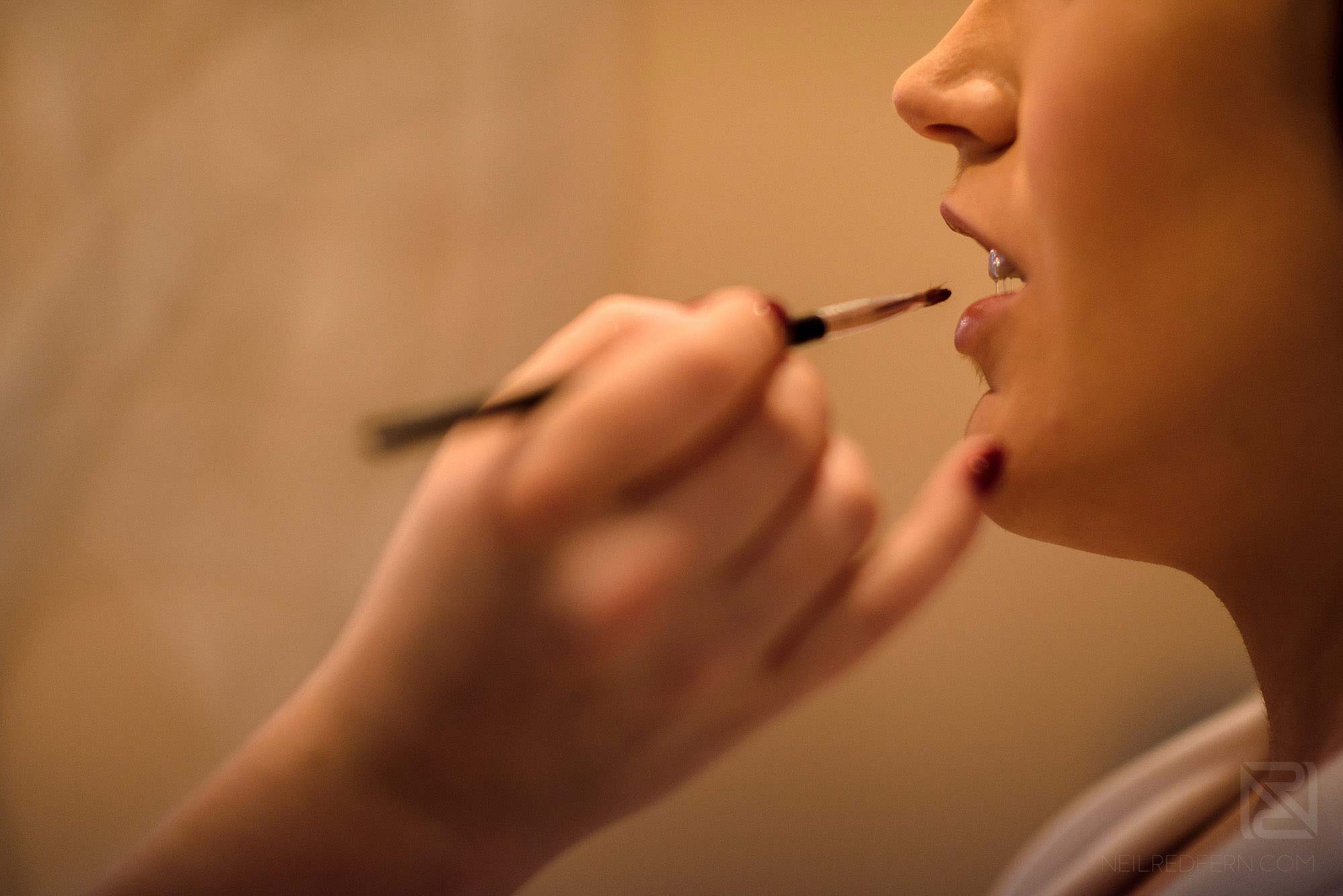 bride having lip stick applied on morning of wedding at Rowton Hall