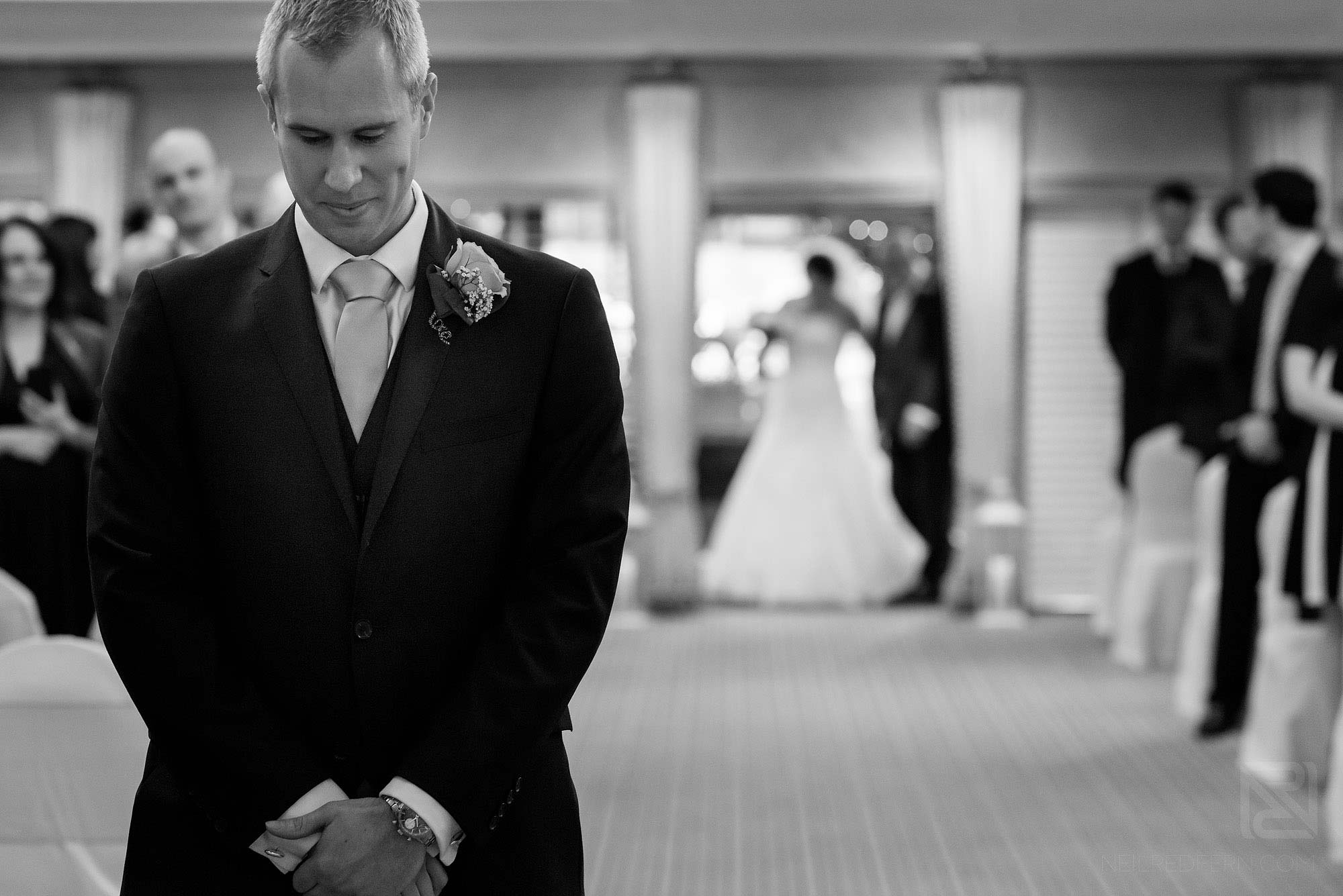 groom looking nervous as bride walks down aisle at Rowton Hall