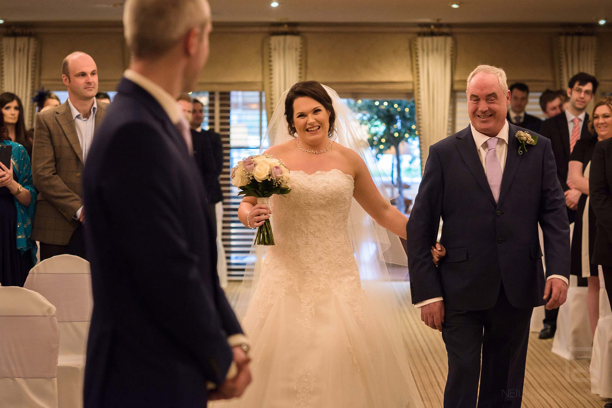 bride looking at groom as she walks down the aisle at Rowton Hall wedding