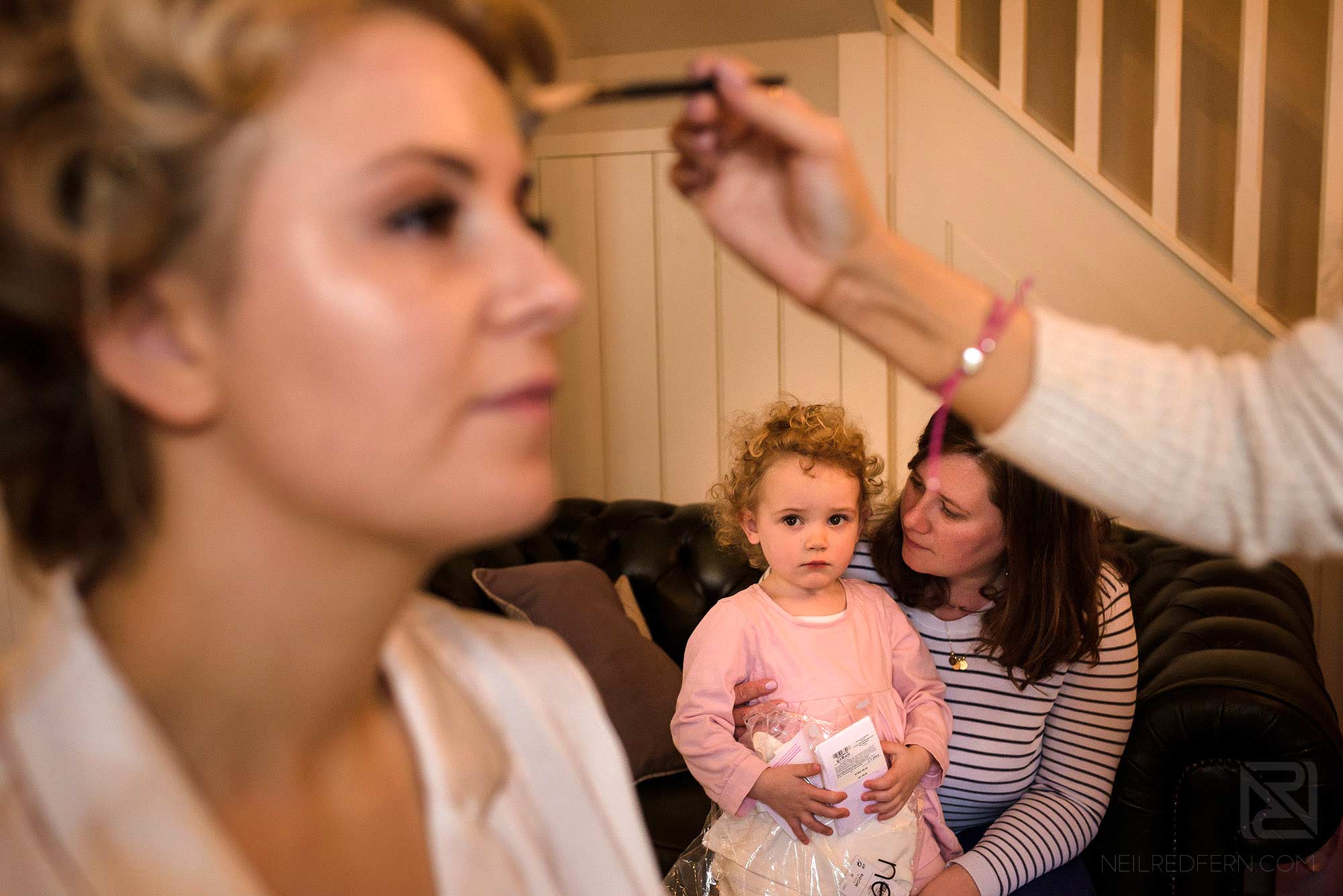 bride having make up put on with flower girl