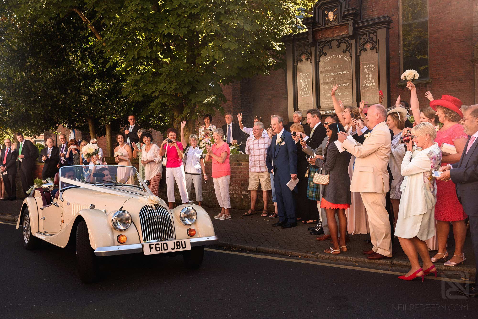 bride and groom leaving church in wedding car