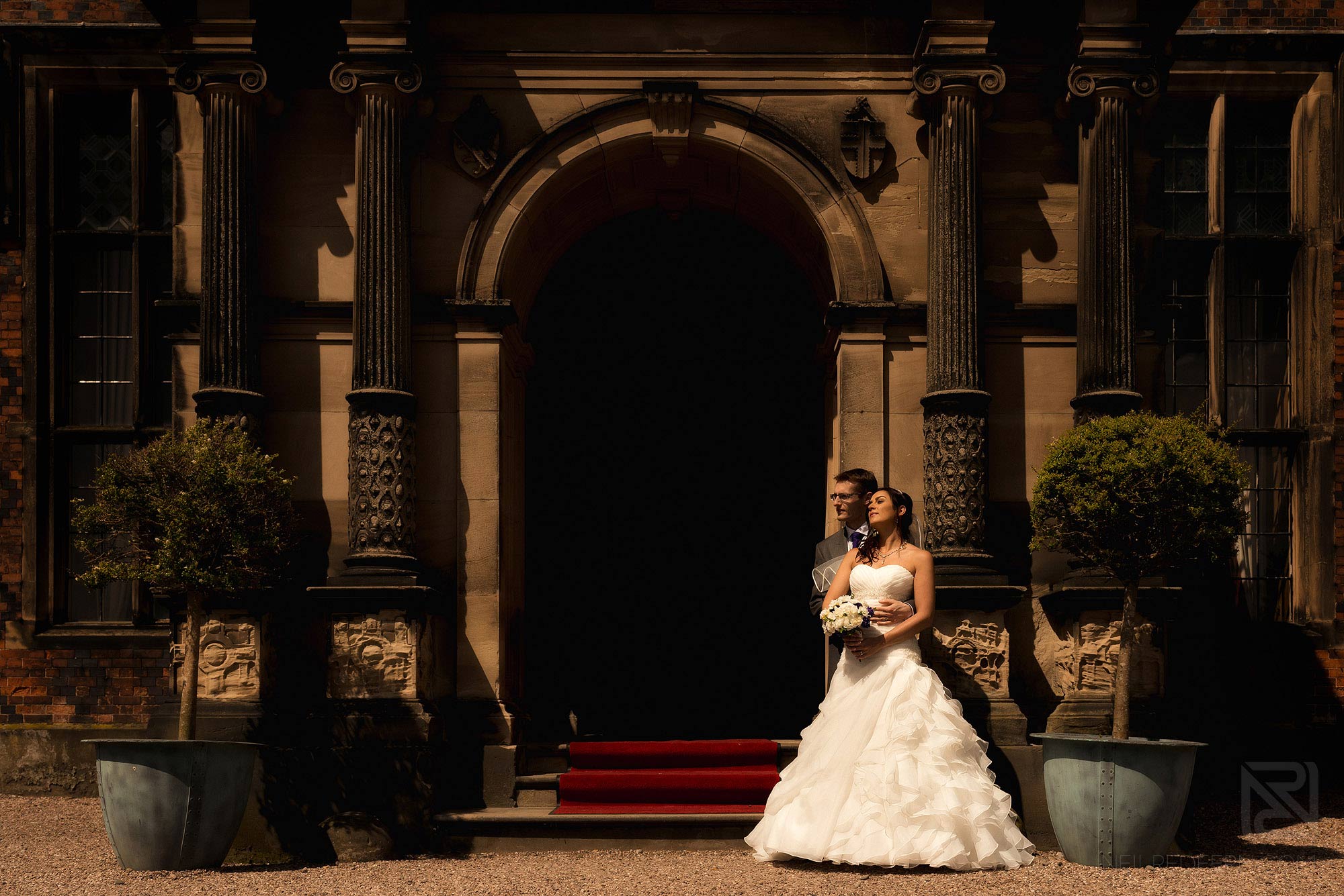 bride and groom stood outside Arley Hall in sunshine