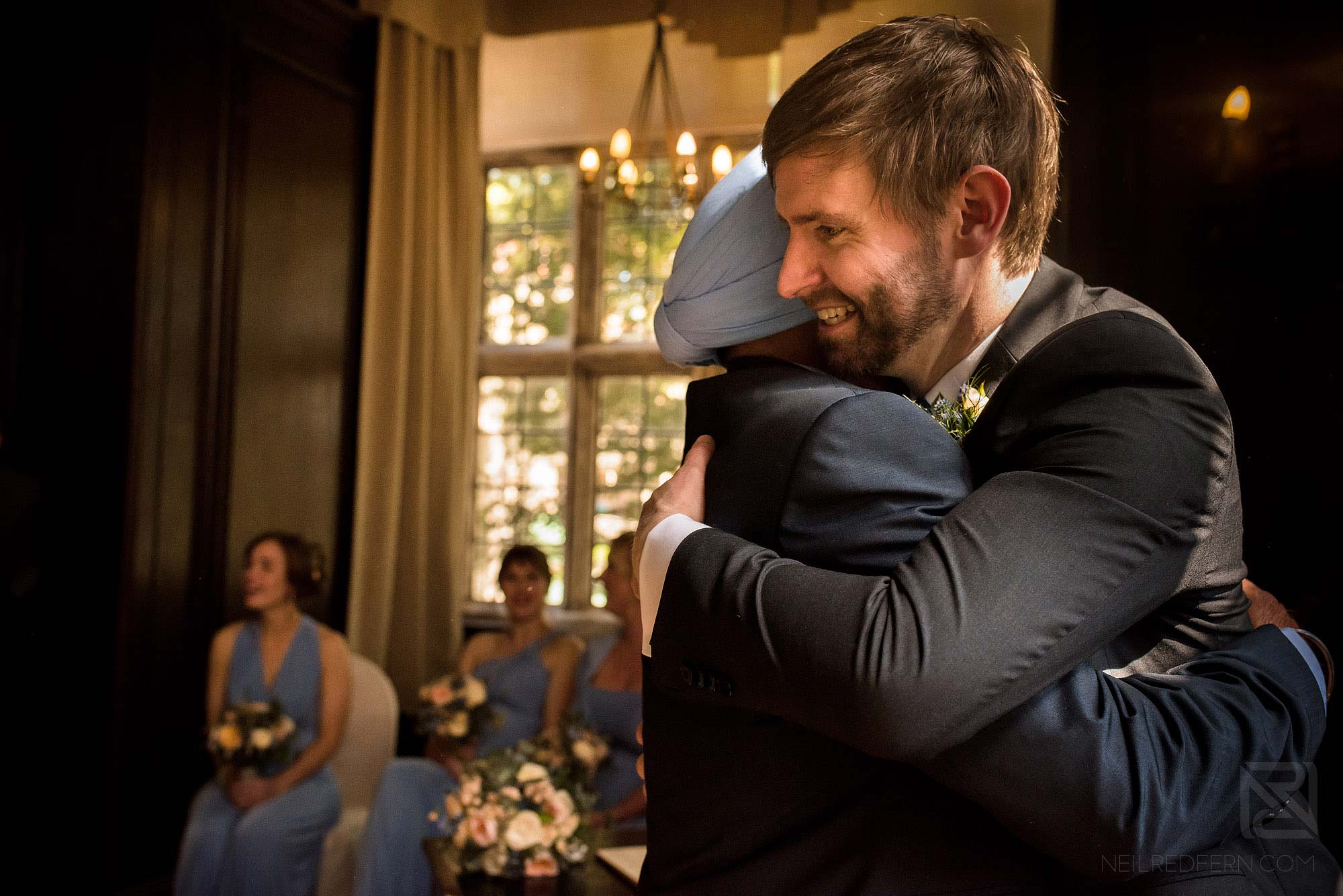 groom hugging a friend after signing of the register