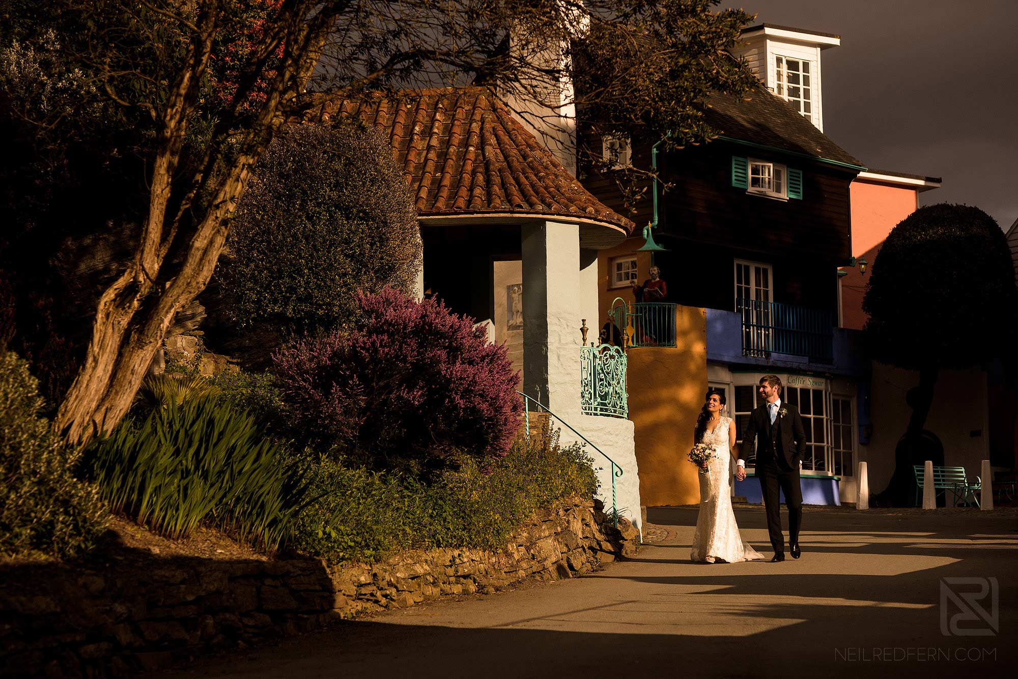 bride and groom on wedding day walking through Portmeirion village