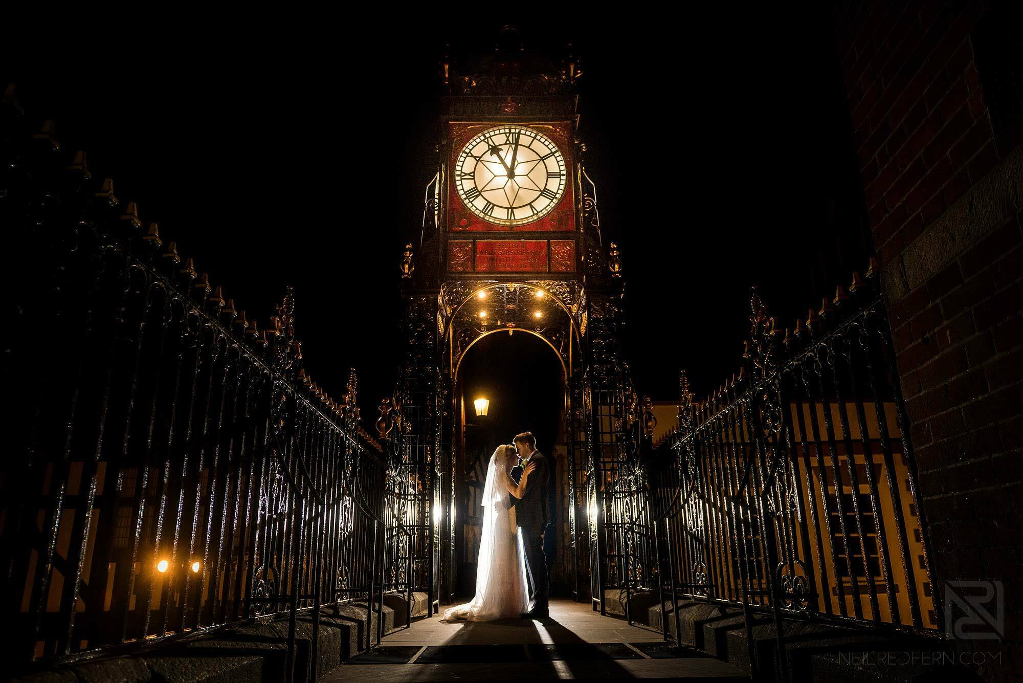 evening portrait of bride and groom under clock in Chester