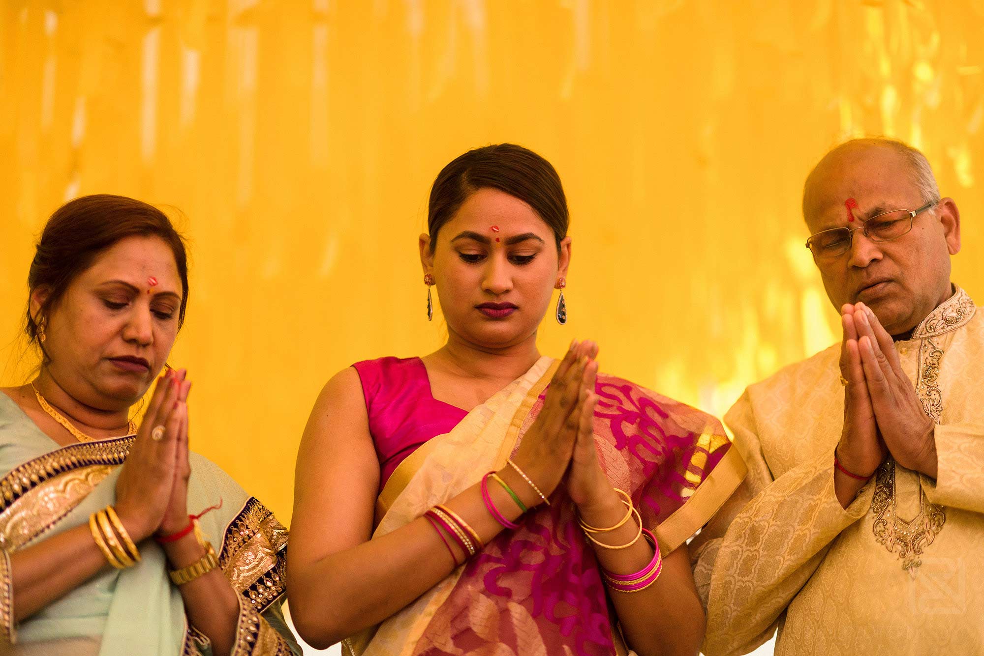 bride and parents praying during Haldi ceremony