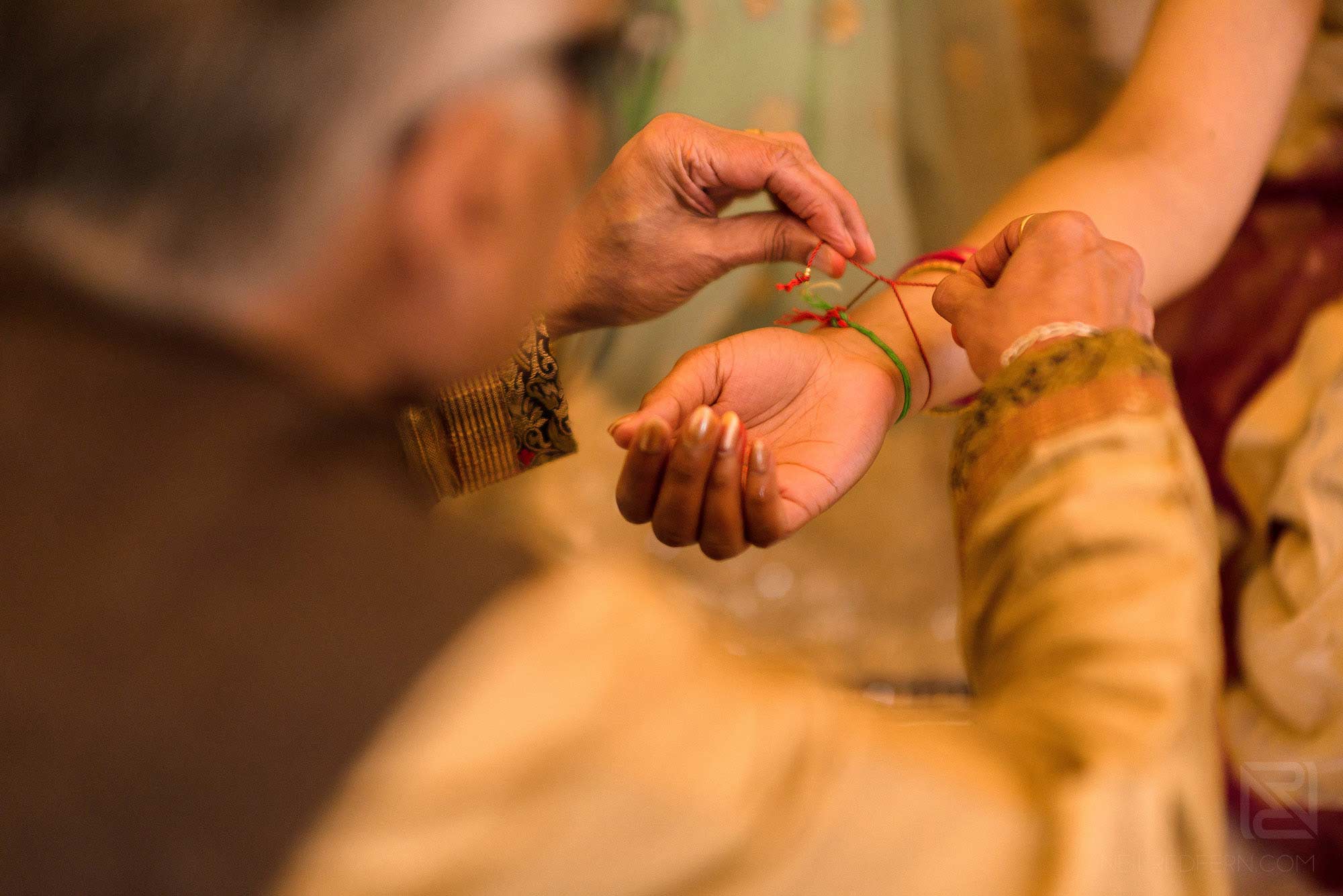 close up of Priest tying string on bride's hand