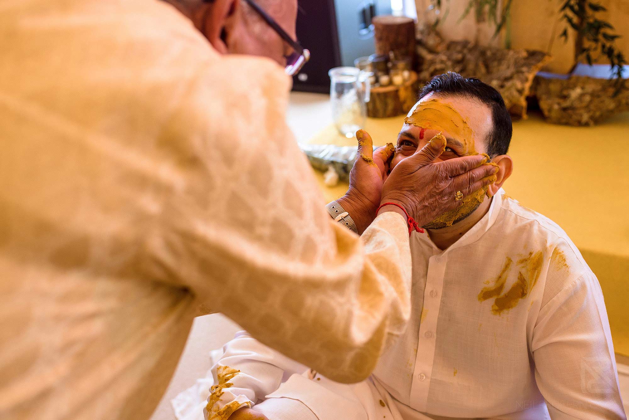 wedding guest putting turmeric on groom's face
