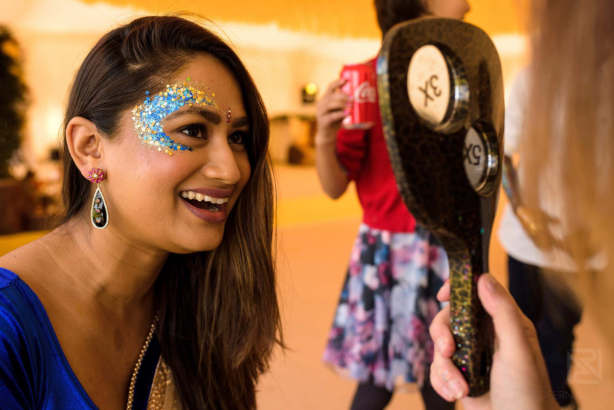 bride laughing with glitter on face at Haldi ceremony