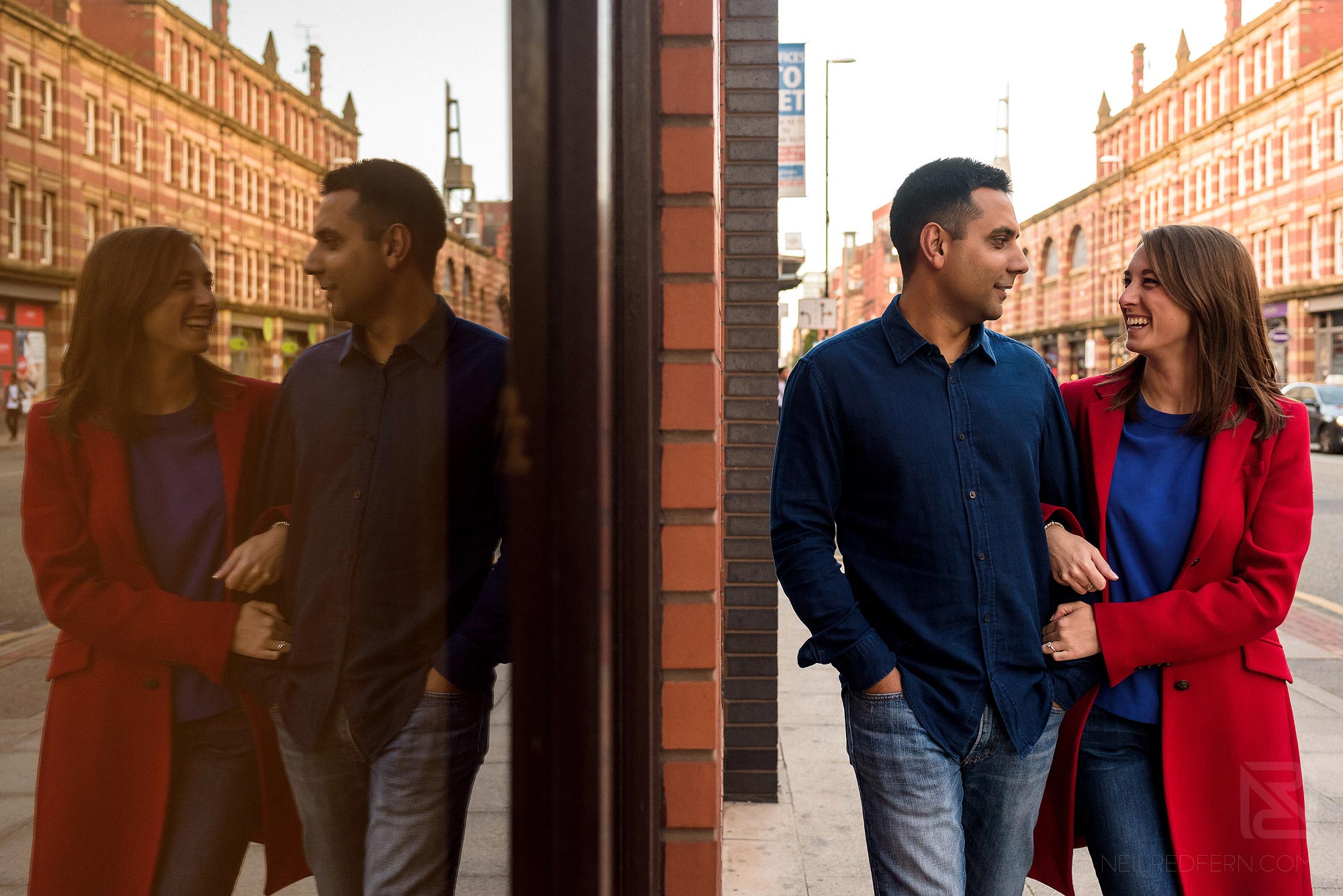Manchester city centre engagement shoot 7 reflection of couple walking down Deansgate on engagement shoot in Manchester city centre