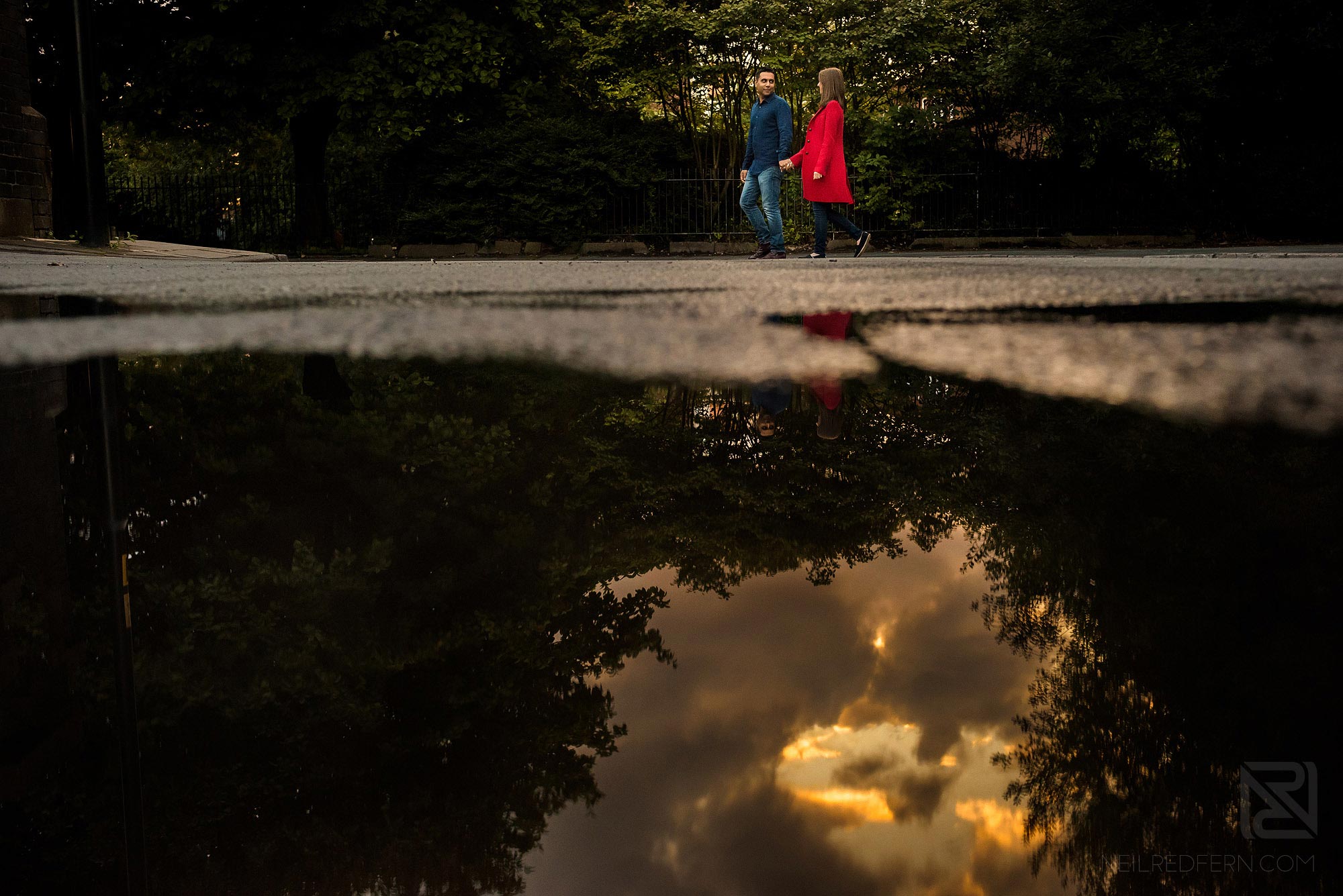 Manchester city centre engagement shoot 9 couple walking down street with reflection in puddle