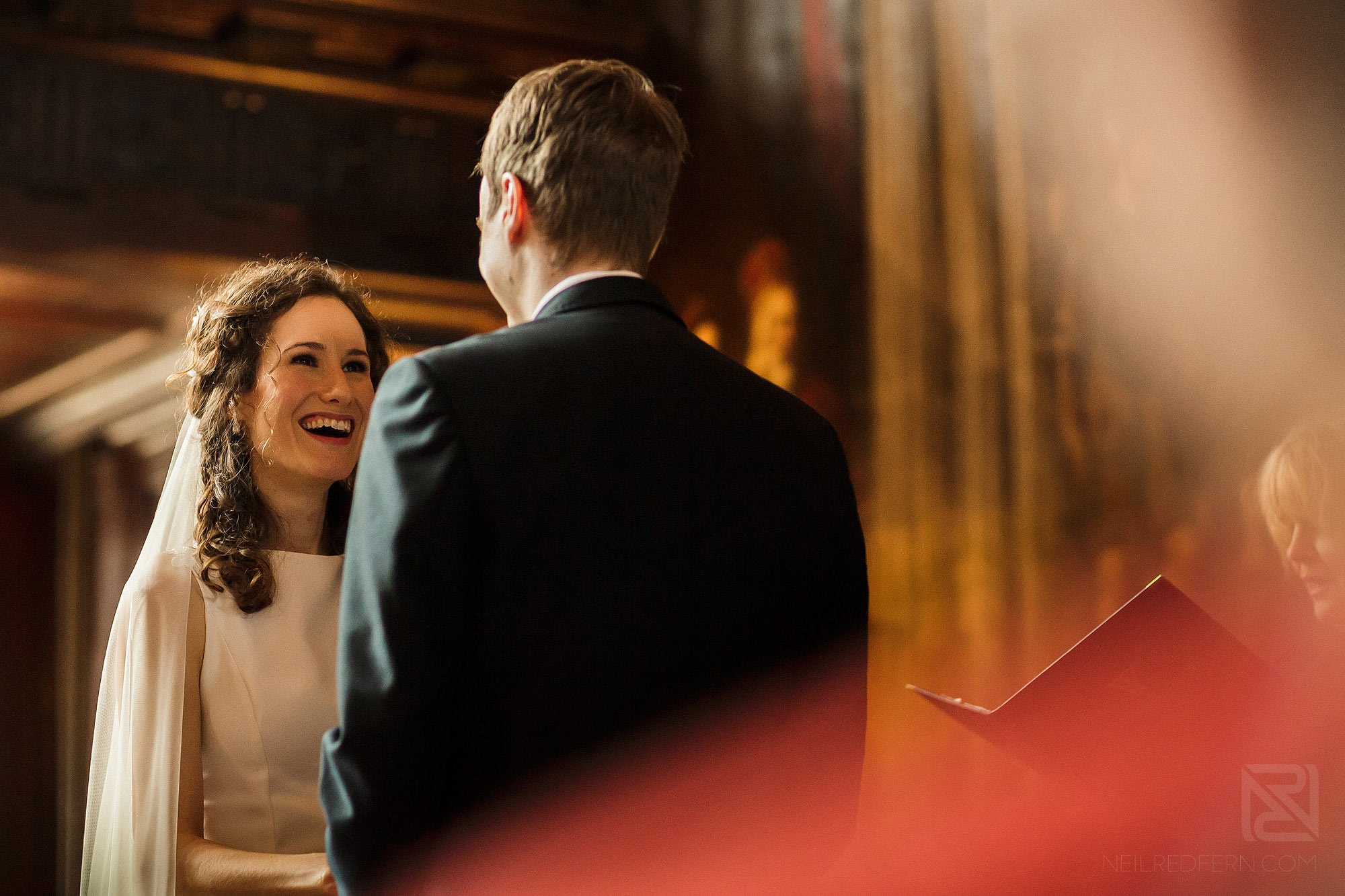 bride laughing with groom during wedding ceremony at Adlington Hall