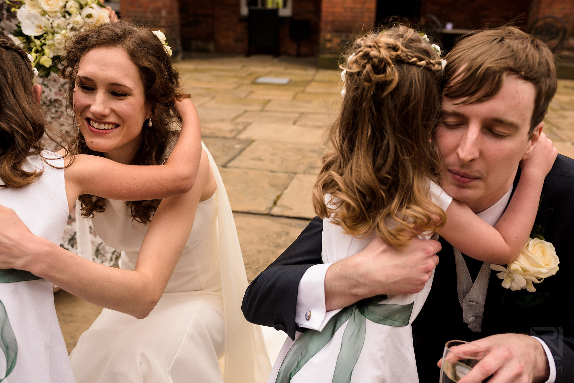 bride and groom hugging flower girls