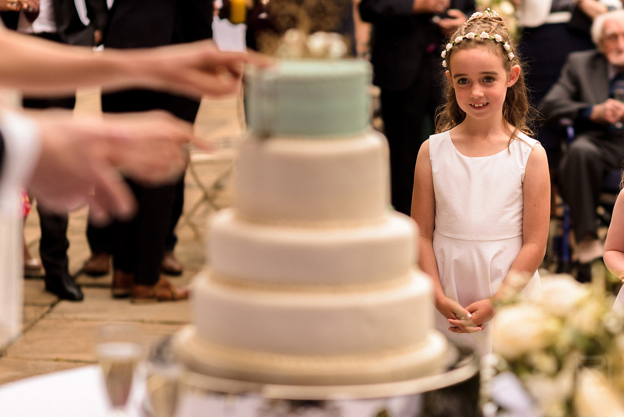 flower girl watching cutting of cake at wedding 