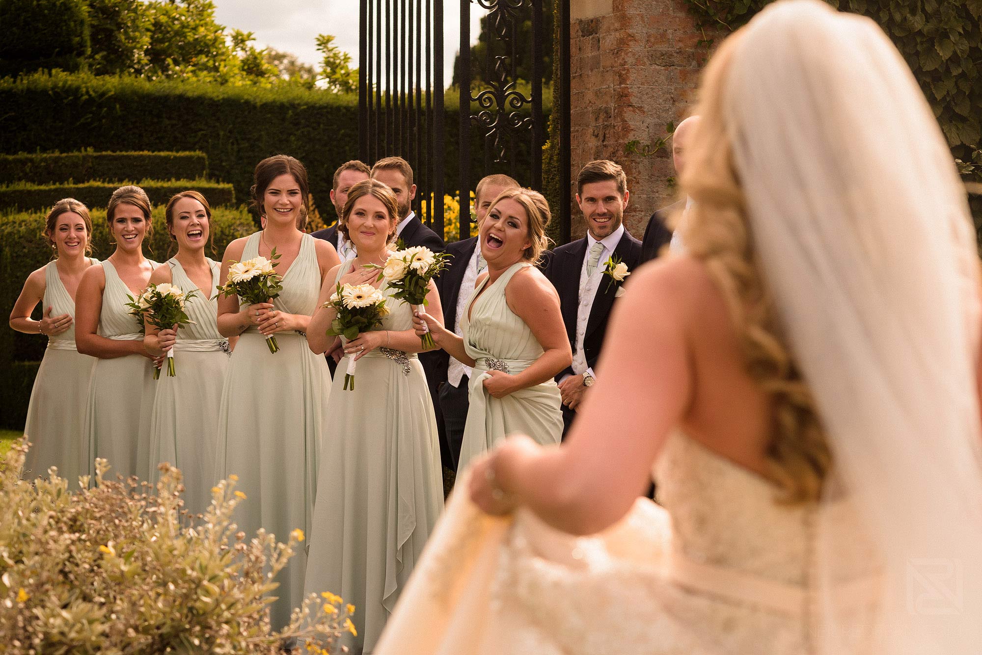 Summer wedding at Arley Hall 10 bridesmaids looking at bride
