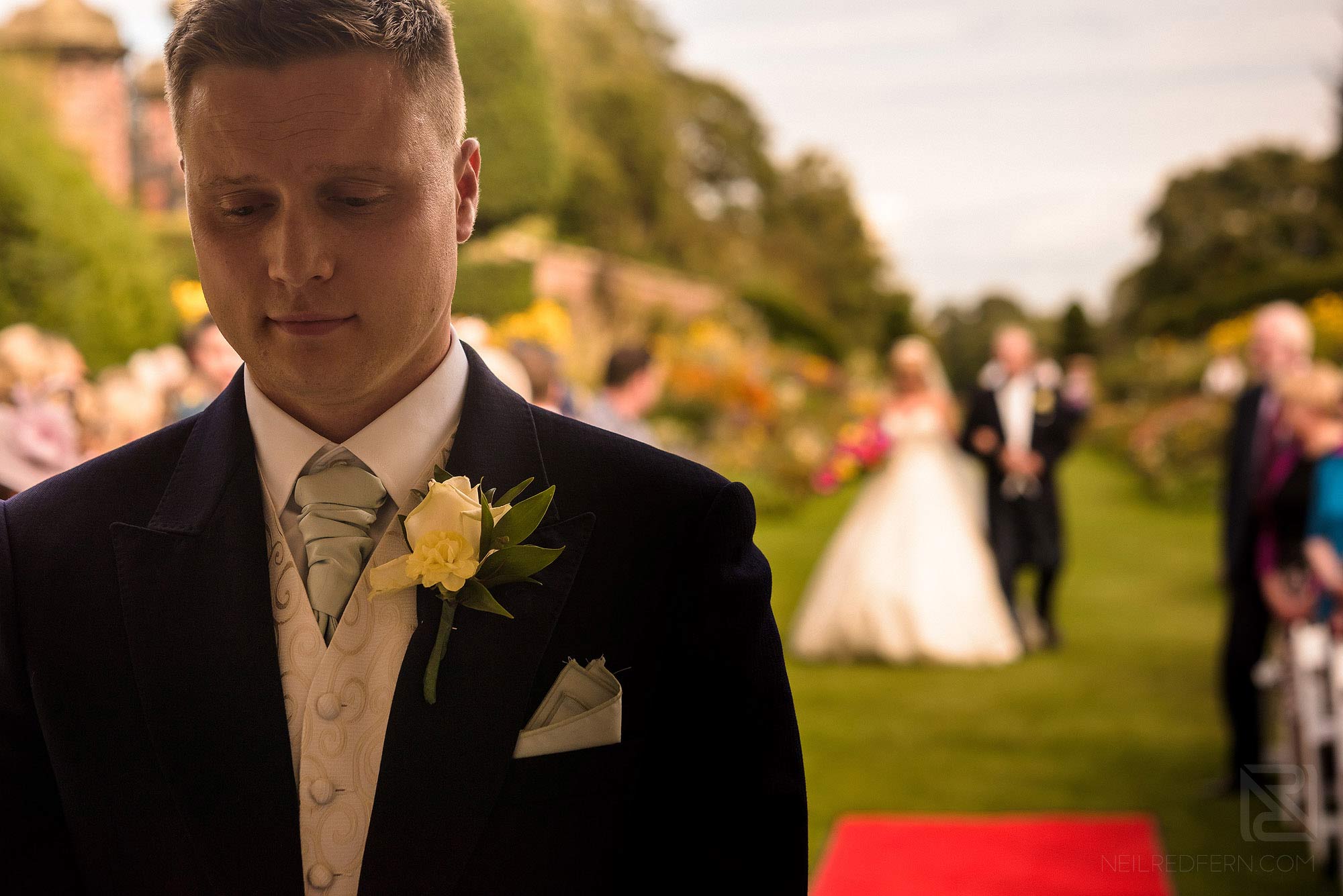 Summer wedding at Arley Hall 11 groom waiting at top of aisle during outside wedding ceremony