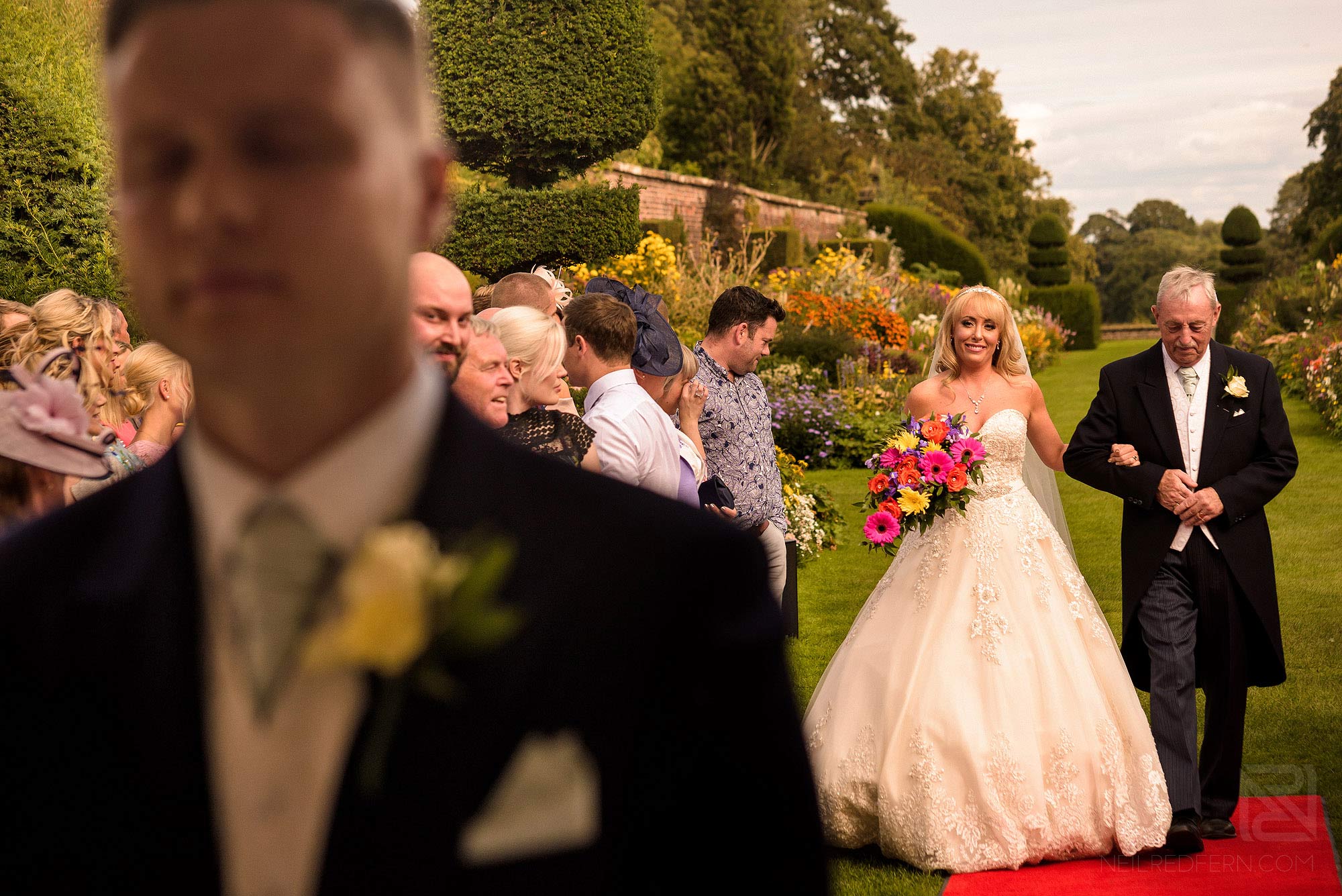 Summer wedding at Arley Hall 12 bride walking down the aisle at outside wedding ceremony