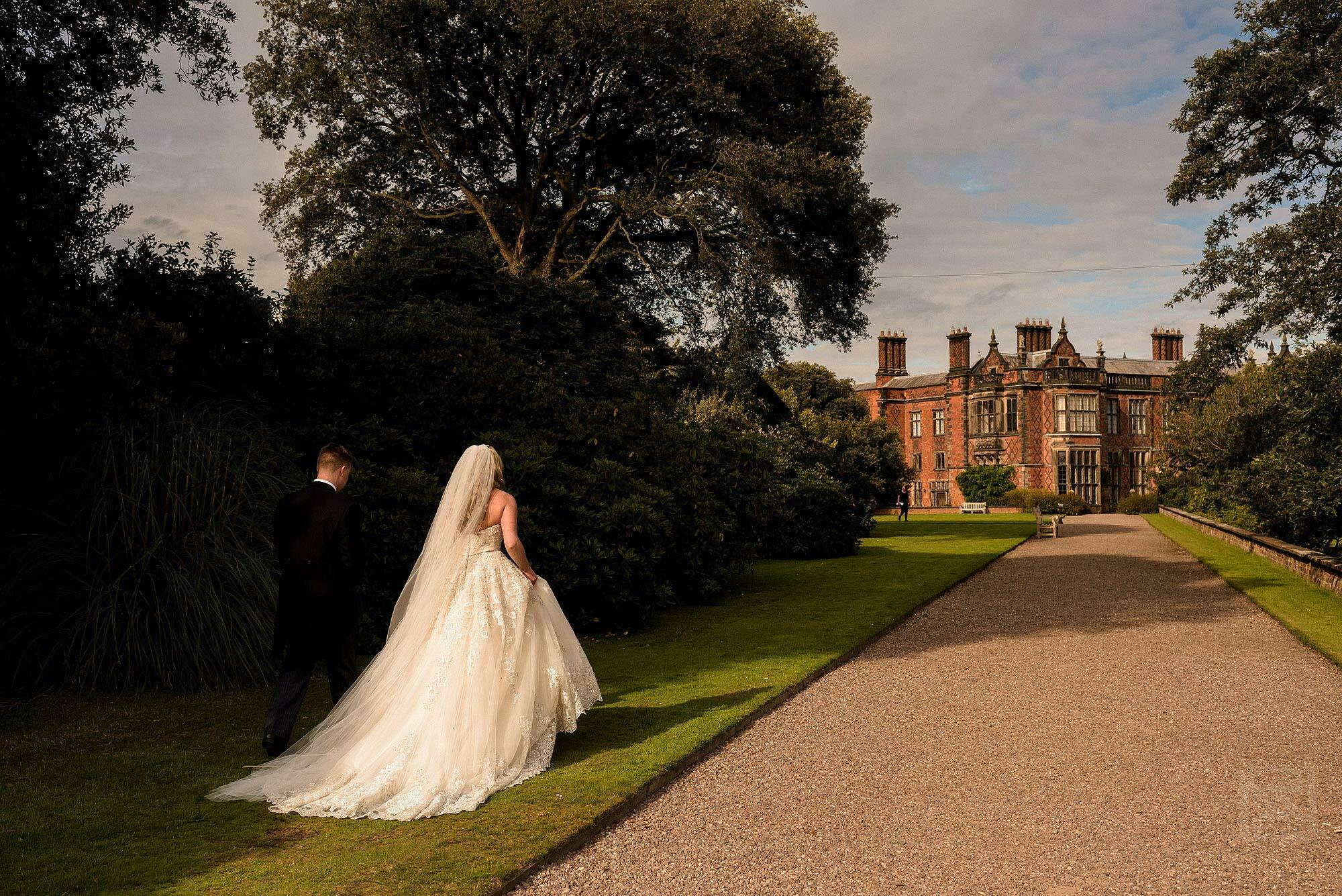 Summer wedding at Arley Hall 17 newlyweds walking towards Arley Hall