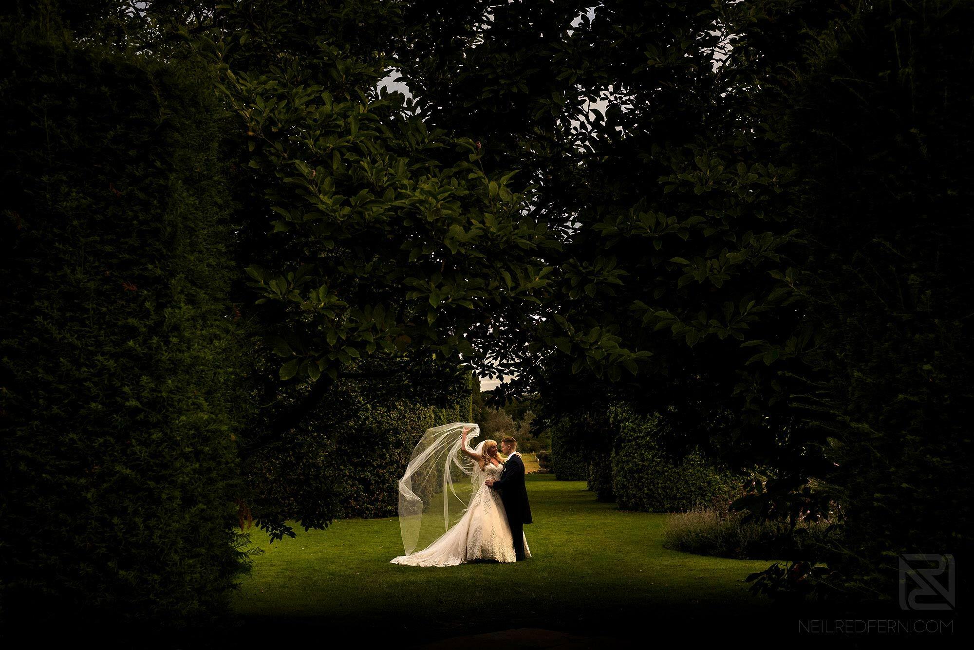 dramatic photograph of bride and groom with veil blowing in wind