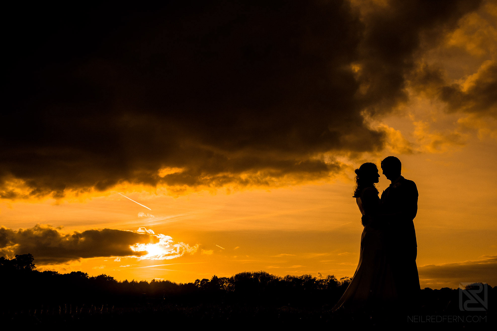 silhouette photograph of bride and groom at sunset