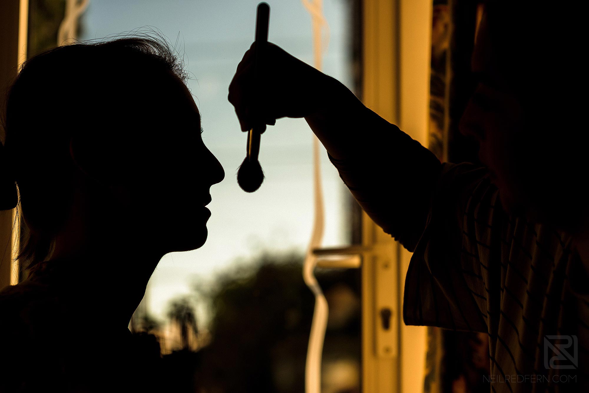 silhouette photograph of bride having make-up put on