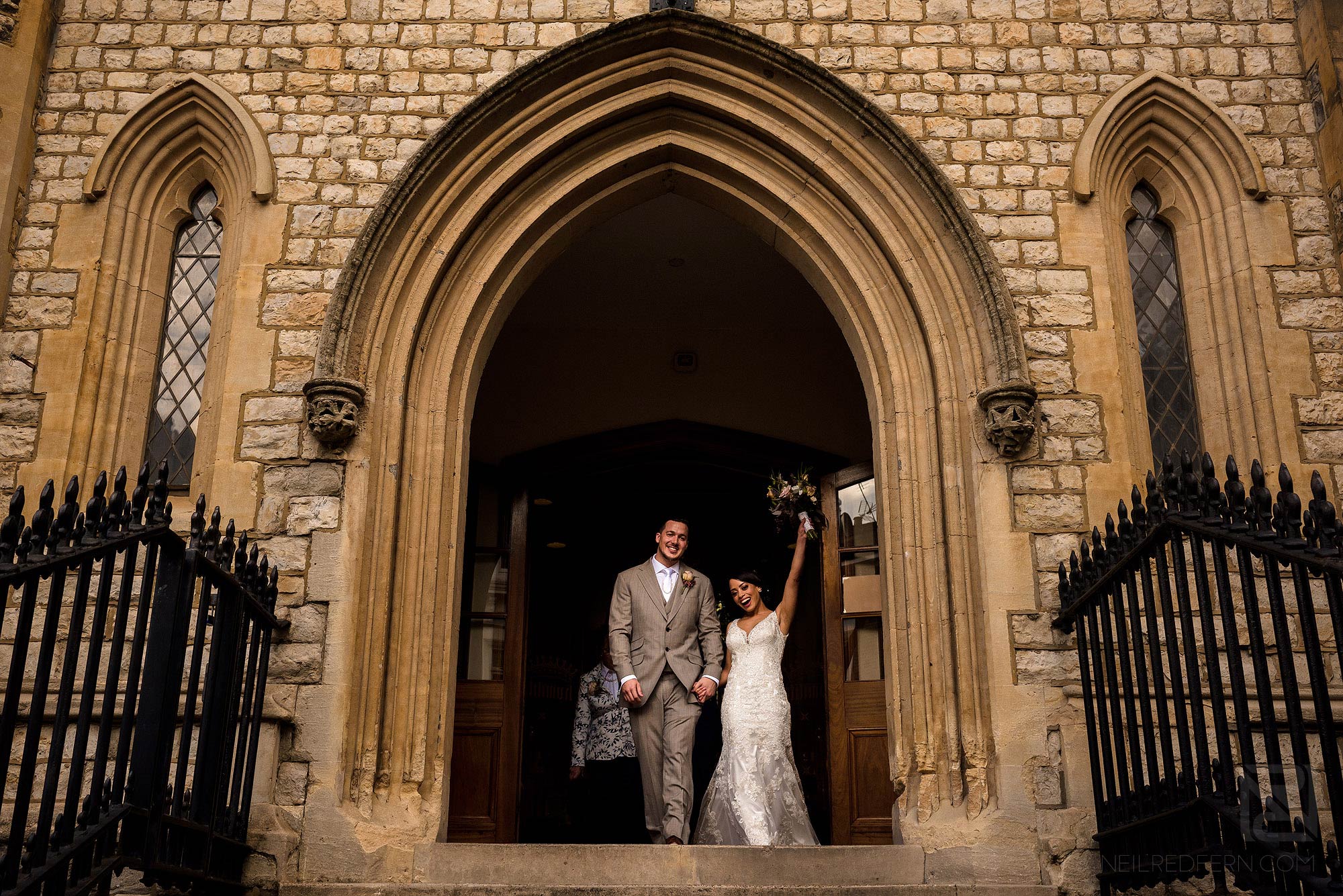 bride waving bouquet in the air leaving church
