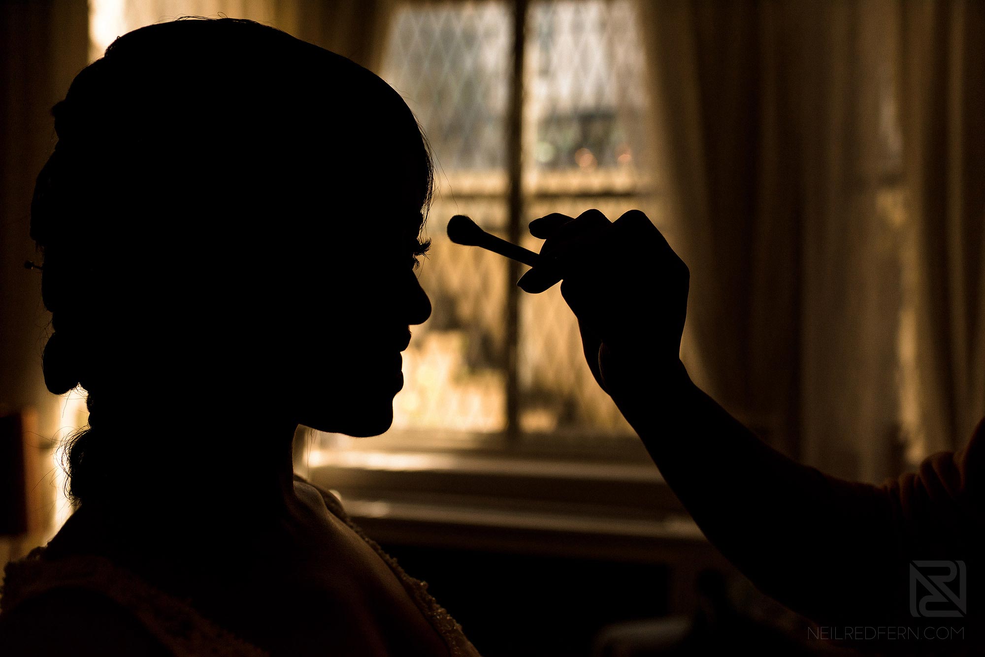 silhouette photograph of bride having make-up put on