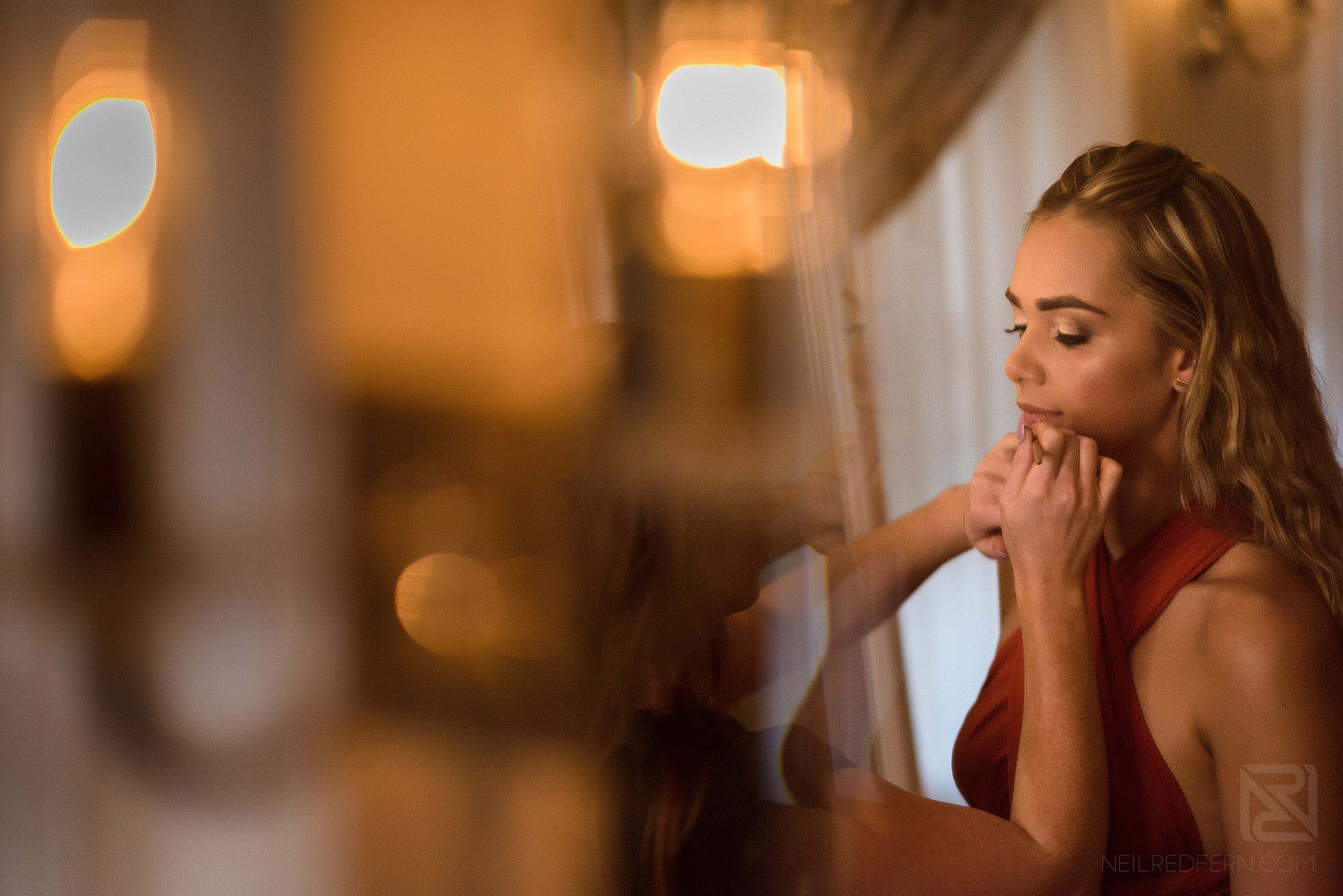 bridesmaid putting on lipstick on morning of wedding