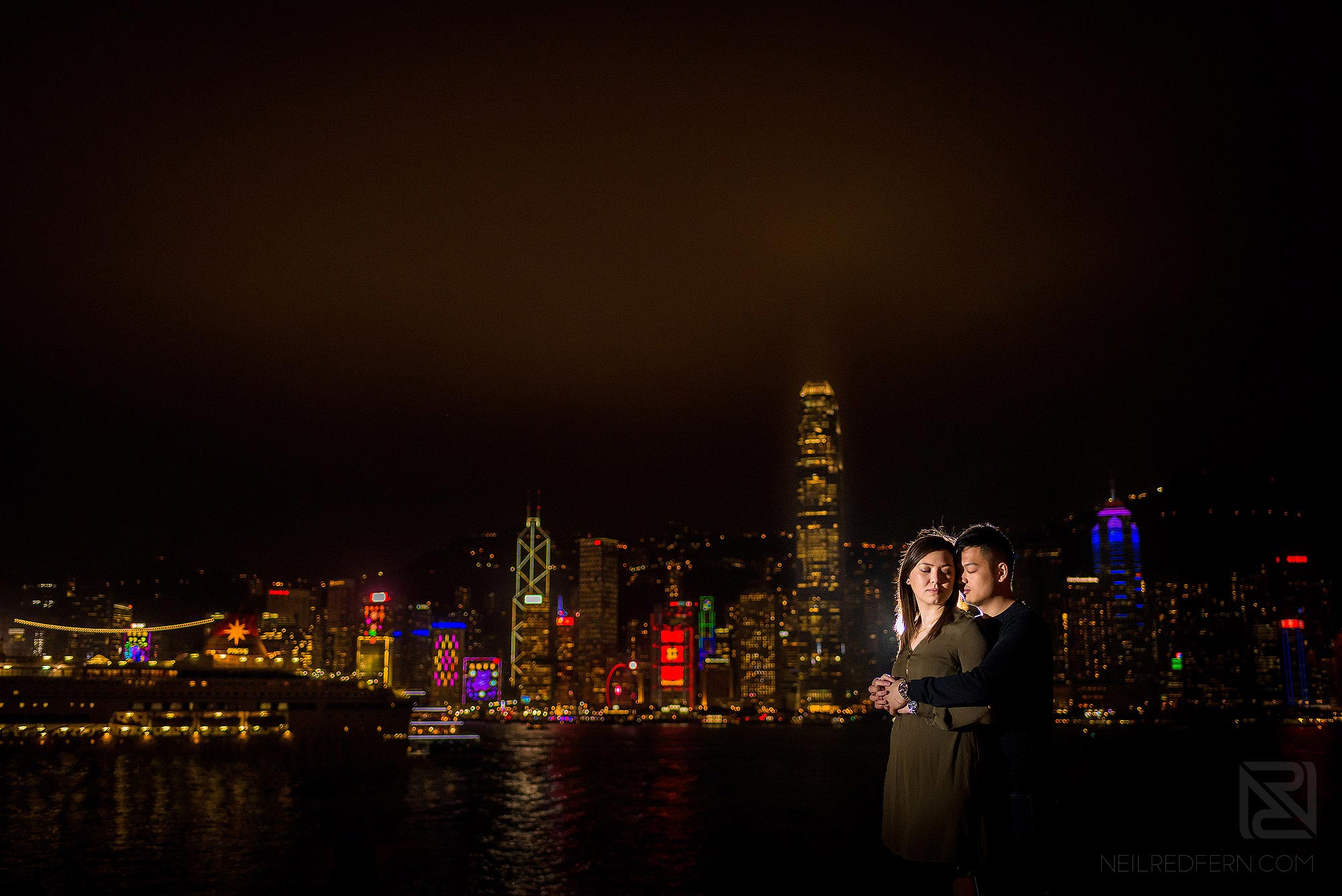 off camera flash portrait of bride and groom in front of Victoria Harbour in Hong Kong