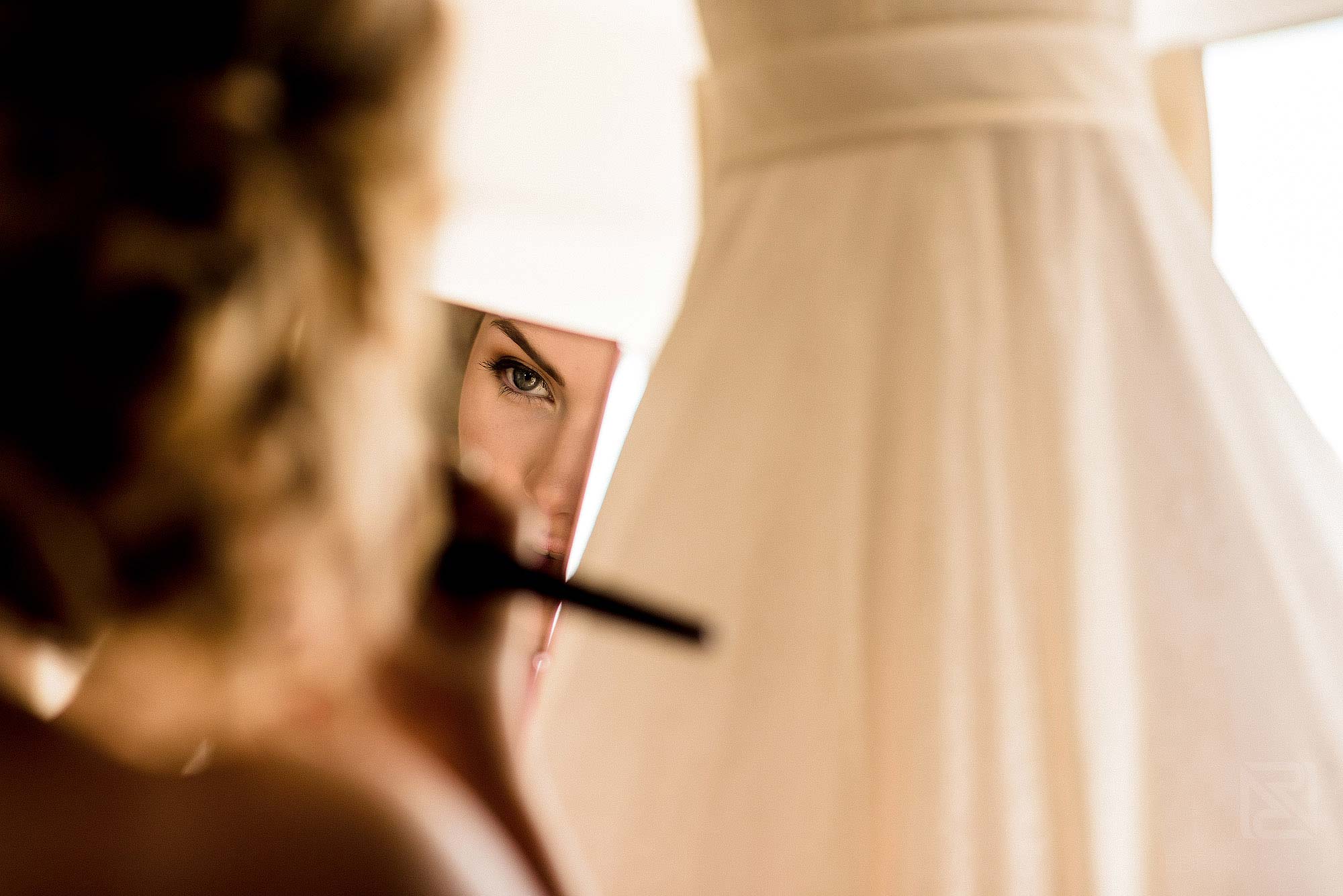 creative photograph of bridesmaid getting ready in front of wedding dress