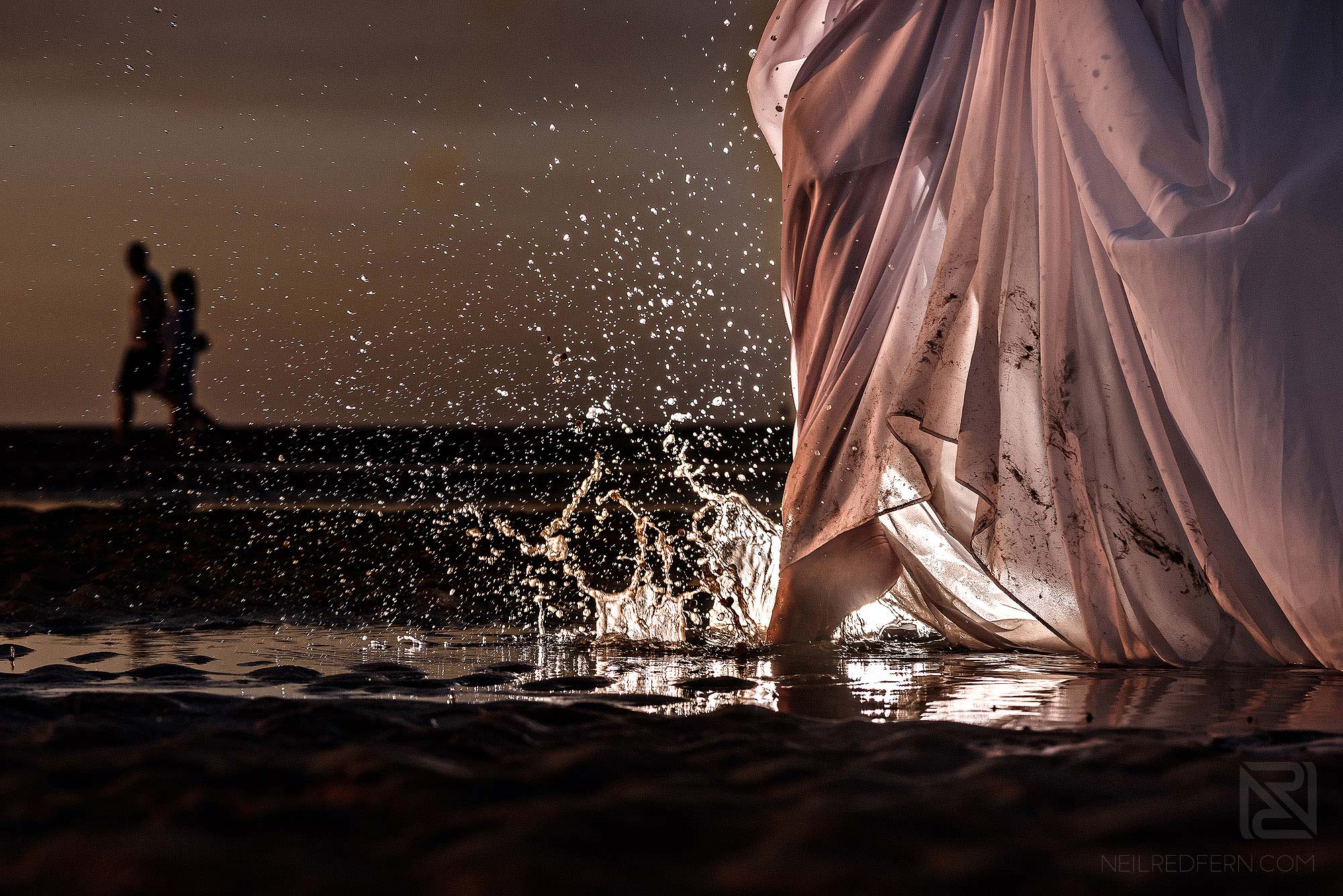 Trash the dress shoot on the beach 5 creative photograph of bride walking through water on beach