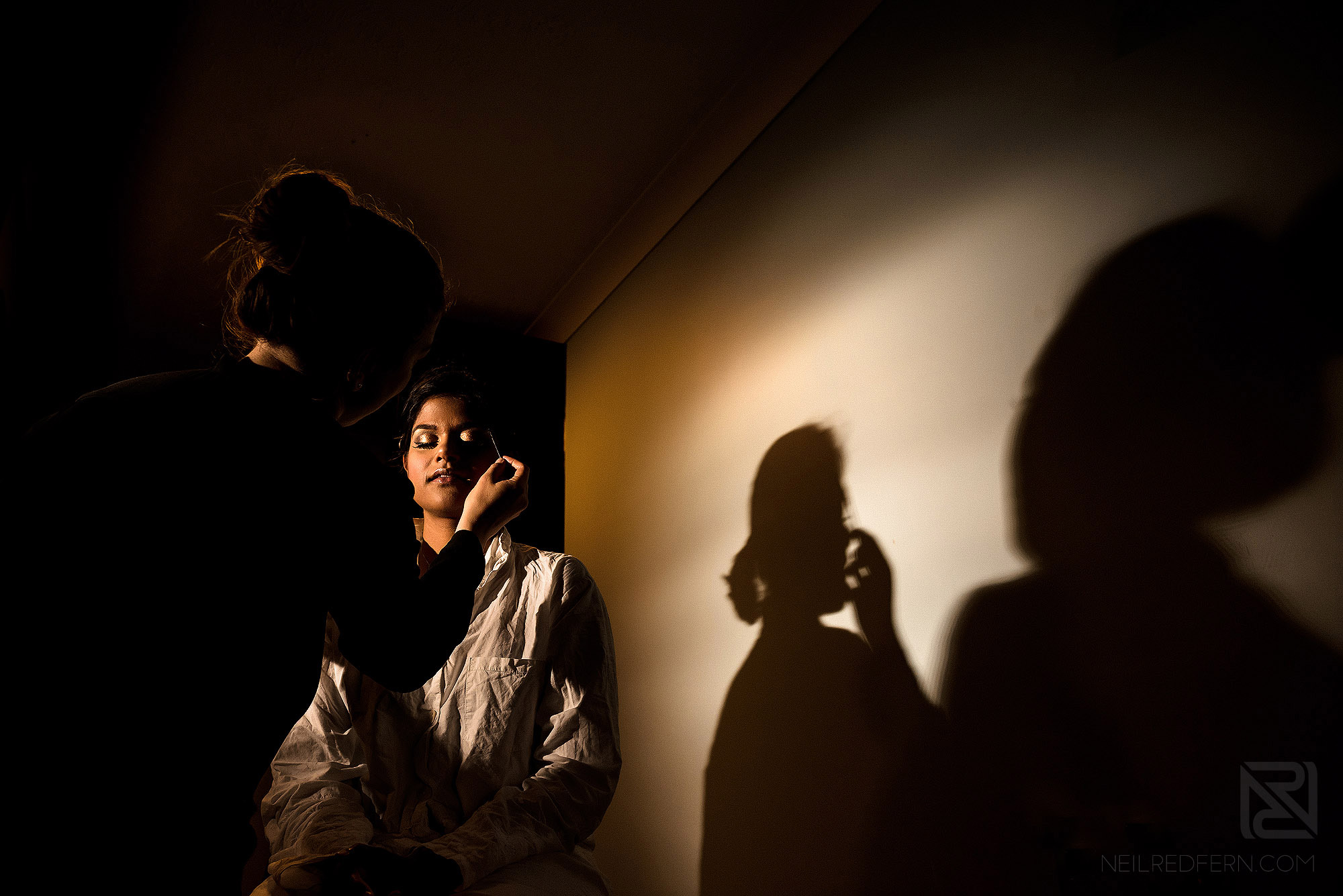 off camera flash photograph of bridesmaid having make-up put on