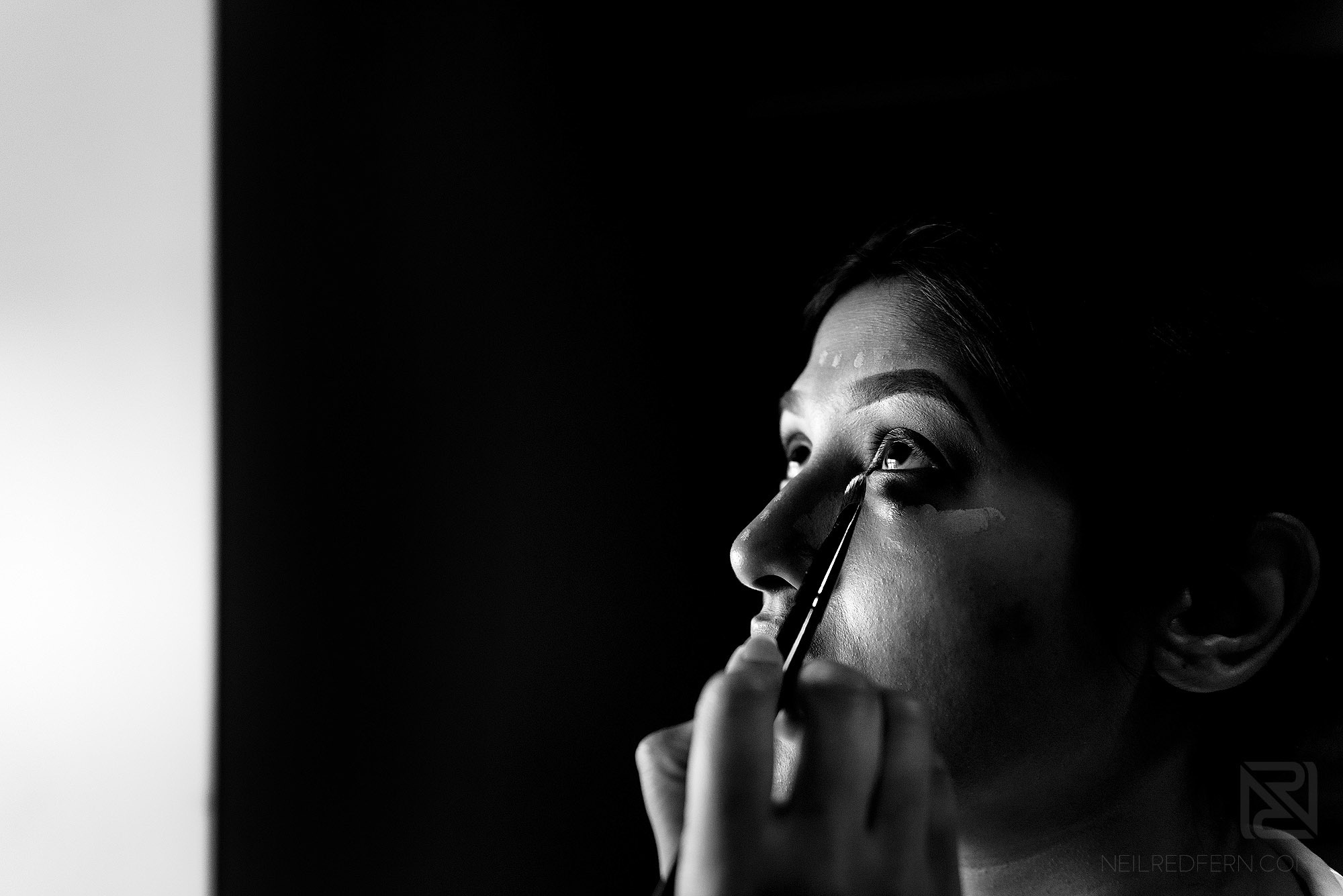 black and white photograph of bride having make-up put on