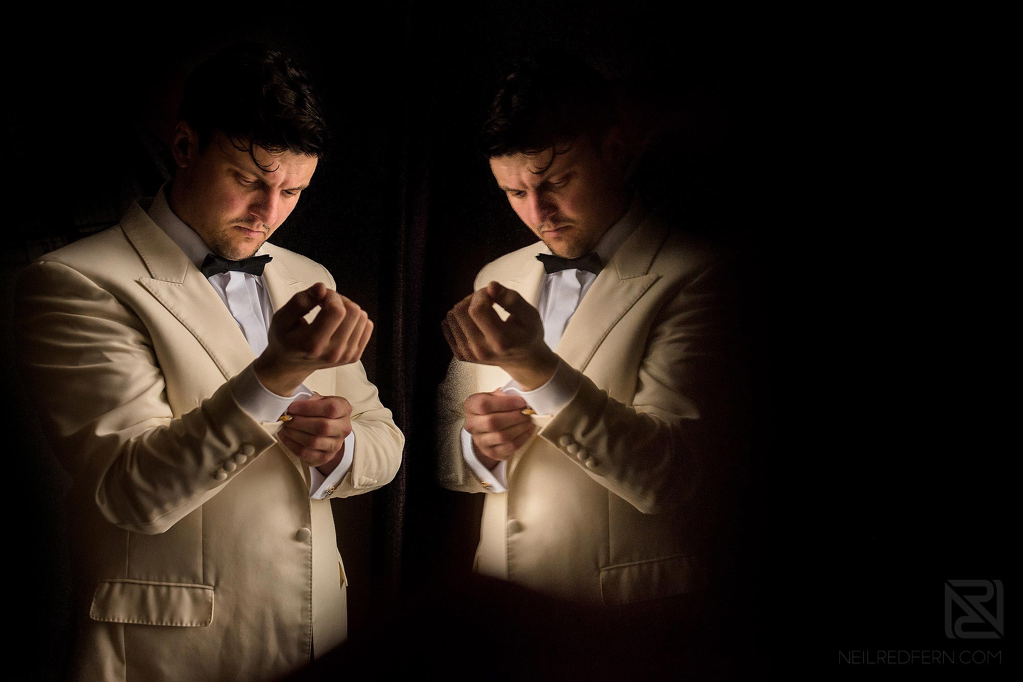 creative reflection photograph of groom putting on cufflinks 