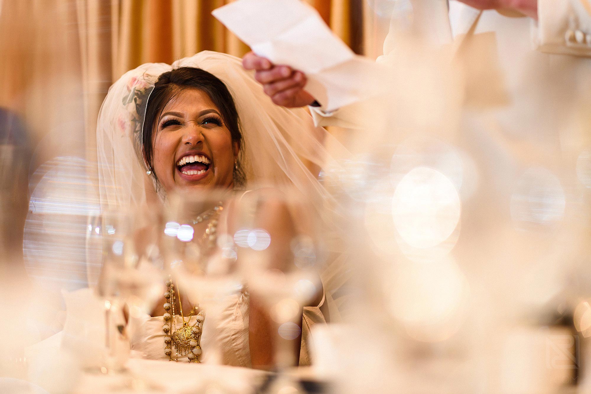 bride laughing during groom's wedding speech